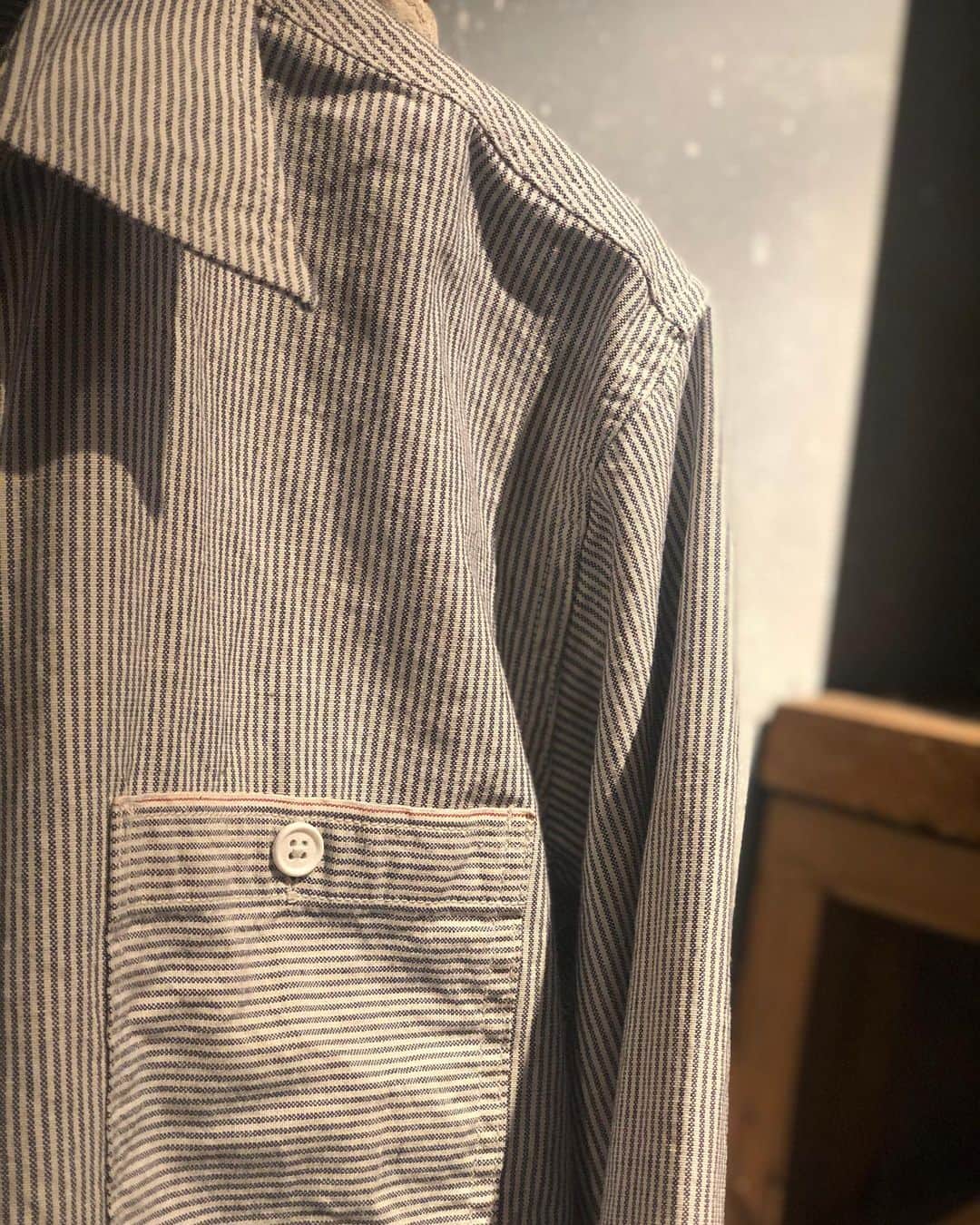 PORT of CALL Cafe&Store Tokyoのインスタグラム：「【BANKS JOURNAL PROJECTS】 STYLE CODE : PALS 0002 STYLE NAME : SELVAGE LS SHIRT MADE IN JAPAN ¥20,350  オーバーサイズでコーディネイトの幅が広いシャツ。 ワークのシャツジャケットとドレスシャツを融合したステッチワークとディテールが、シンプルさの中に違いを演出しています。 ジーンズの聖地、岡山で縫製することで、日本製の確かな品質とカジュアルなニュアンスが美しい一枚です。 生地は先染インディゴ糸と生成り糸のストライプを、セルビッチ織り機で織り、【赤耳】仕上げとなっています。 その【赤耳】をポケットと前立て裏に使い、デザインアクセントとなっています。 インディゴなので色の深い味わいと共に、使い込む度にデニムのような色落ちが楽しめ、自分だけの一枚に育て上げてください。  「セルビッチ」:  デニム生地の端、通称「耳」と呼ばれる部分のことを指し、旧式の力織機を使用して織られた、生地端にほつれ止めがされたデニム生地のこと。 このほつれ止めが施された生地端の部分に、赤いラインの入っているものが通称【赤耳】と呼ばれています。 一般的に「セルビッチデニムは高級」というイメージがありますが、なぜ高価になるかには理由があります。 「生産効率が悪い」ということです。 旧式の織機を使用して生産されるセルビッチデニムは、その生地を織る為に通常のデニム生地の５倍以上の時間を必要とします。職人が何度もチェックをしながら1時間で数ｍしか織ることができず、さらには織りキズなどロスが出ることも多いので、とても貴重なデニム生地といえます。 この「生地を織るのに時間がかかる」ということが一つの理由です。  #banksjournal﻿ #banksjournalcollection #BJP #sustainable #craftsmanship #repurpose」