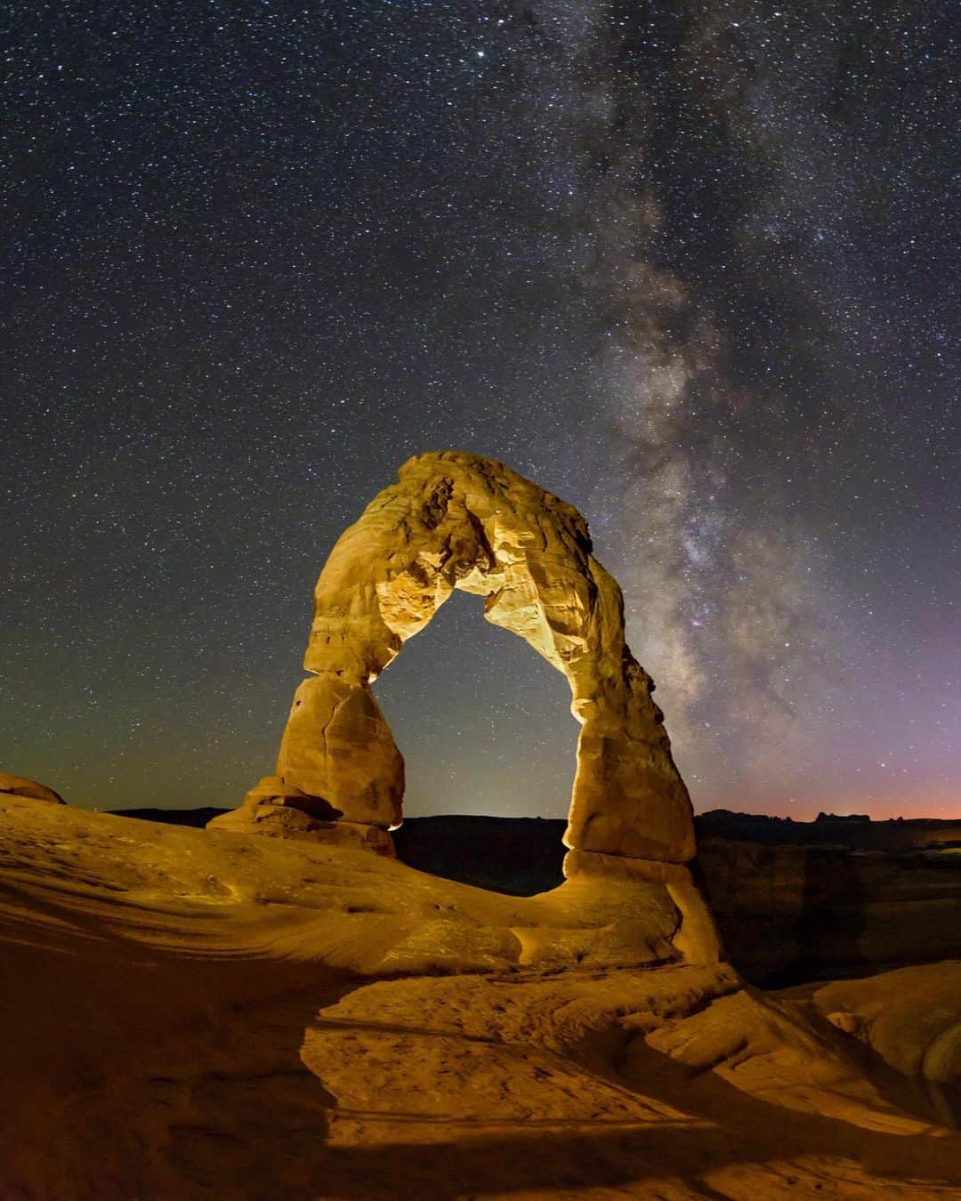 National Geographic Travelさんのインスタグラム写真 - (National Geographic TravelInstagram)「Photo by @babaktafreshi / Swipe to see the entire view of Delicate Arch at night. The Milky Way appears above the desert landscape of Arches National Park as the last glow of evening twilight fades to darkness. The 52-foot-tall (16-meter-tall), freestanding natural arch, illuminated by a portable light in this exposure, is an iconic view of the American Southwest. This makes it a very popular spot both day and night, despite the steep uphill hike.  Explore more of the world at night photography @babaktafreshi. #utah #nightsky #twanight」1月26日 0時48分 - natgeotravel
