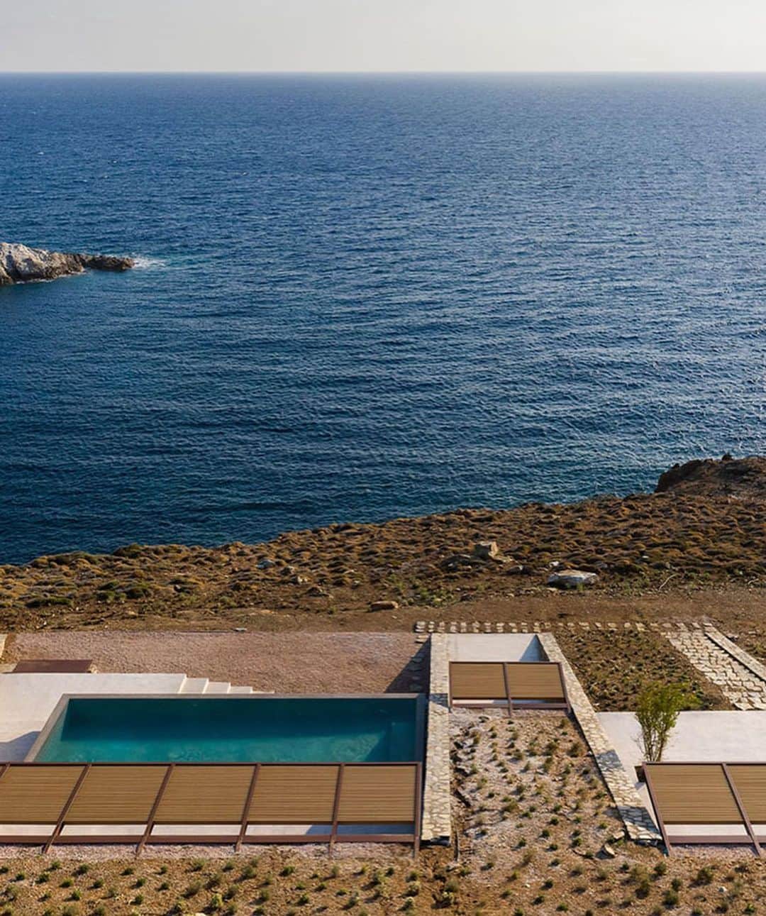 The Cool Hunterさんのインスタグラム写真 - (The Cool HunterInstagram)「Designed by Athens-based @moldarchitects nCAVED is currently high on our list of genuinely original yet refreshingly unpretentious vacation residences. The drama of the severe rocky landscape is repeated with dramatic skill in the chiselled strictness of the building.  Completed in 2020, nCAVED’s 340 square metres (3,660 sq.ft) of space disappear into the rock in a protected cove on the island of Serifos. From the outside it brings to mind the entrance of a pyramid or tomb. Yet from the inside, the living rooms are filled with natural light and afford spectacular views of the Aegean Sea. The strong northerly winds of the sea were one of the key considerations in the planning process that resulted in a dramatic solution providing both extreme shelter and stunning views. (Link in profile) #swipeleft」1月26日 14時37分 - thecoolhunter_