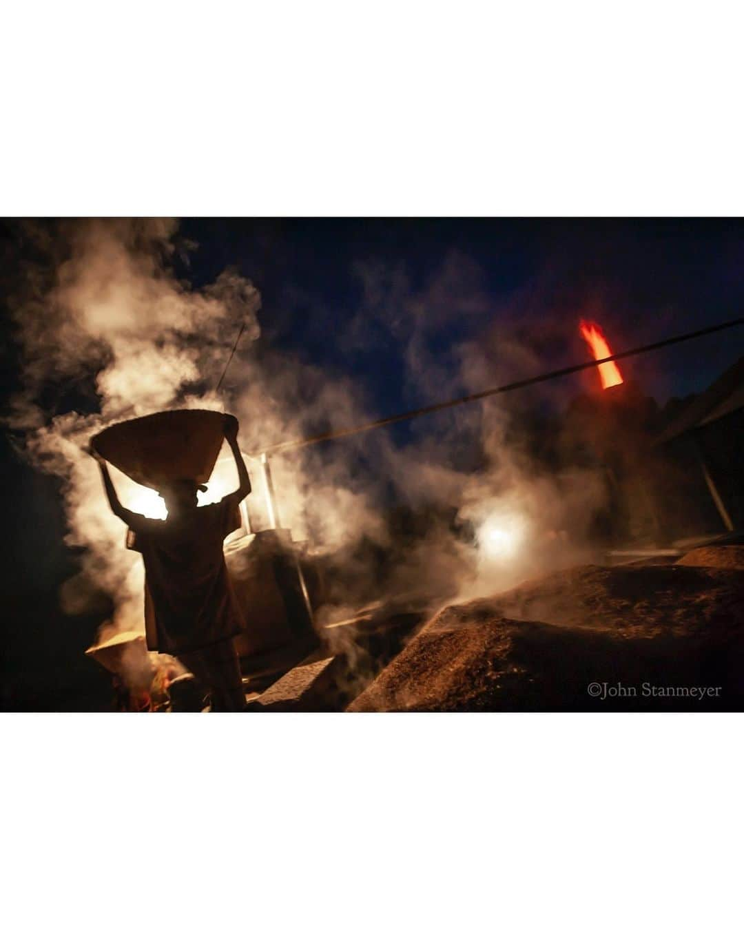 ジョン・スタンメイヤーさんのインスタグラム写真 - (ジョン・スタンメイヤーInstagram)「This photograph is as silhouette’y as I can accept, thankful for the layers of unpleasant interestingness... backlit smoke and rice as in a movie set, but it’s real. So were the actors of humanity. Add a rocket flame-thrower to boil water that pre-cooks rice in its husk to trick the stomach you’ve eaten more than you have, and so presents the evils of poverty and the rising cost of food all in one moment. Pieces of many from a worldwide story I photographed a few years ago for @natgeo, including the village rice processing center in Rangpur, northern Bangladesh. ⠀⠀⠀⠀⠀⠀⠀⠀ Silhouettes bore me. Why? There’s no emotional meaning of purpose nor depth of consciousness. Sleepy picture postcards... someone walking on a sunsetting beach, a landscape with mountains, with a building silhouetted in the foreground... come on. ⠀⠀⠀⠀⠀⠀⠀⠀ Soon, I will begin a series of videos on TikTok and here on Instagram Live called “Ask Me Anything!” I hope to share with working and aspiring photographers how to let go of the boredom state of photography I’m seeing. A repetition that isn’t enlightening us beyond what we already know, and why now, at this moment in history, we need to go into daring and beautiful depth-spaces of visual storytelling that causes us to rethink who we are, where we are going. If not, we will continue the same cycles of war, division, environmental loss, and, yes, uninteresting photography that, for whatever reason we like, limiting ourselves in unending, uninspiring art in little purpose. Harsh? No. Truth. ⠀⠀⠀⠀⠀⠀⠀⠀ #askmeanything #series #beginningsoon #bangladesh #rice #flame #labor follow me on #tiktok @johnstanmeyer」1月28日 14時57分 - johnstanmeyer