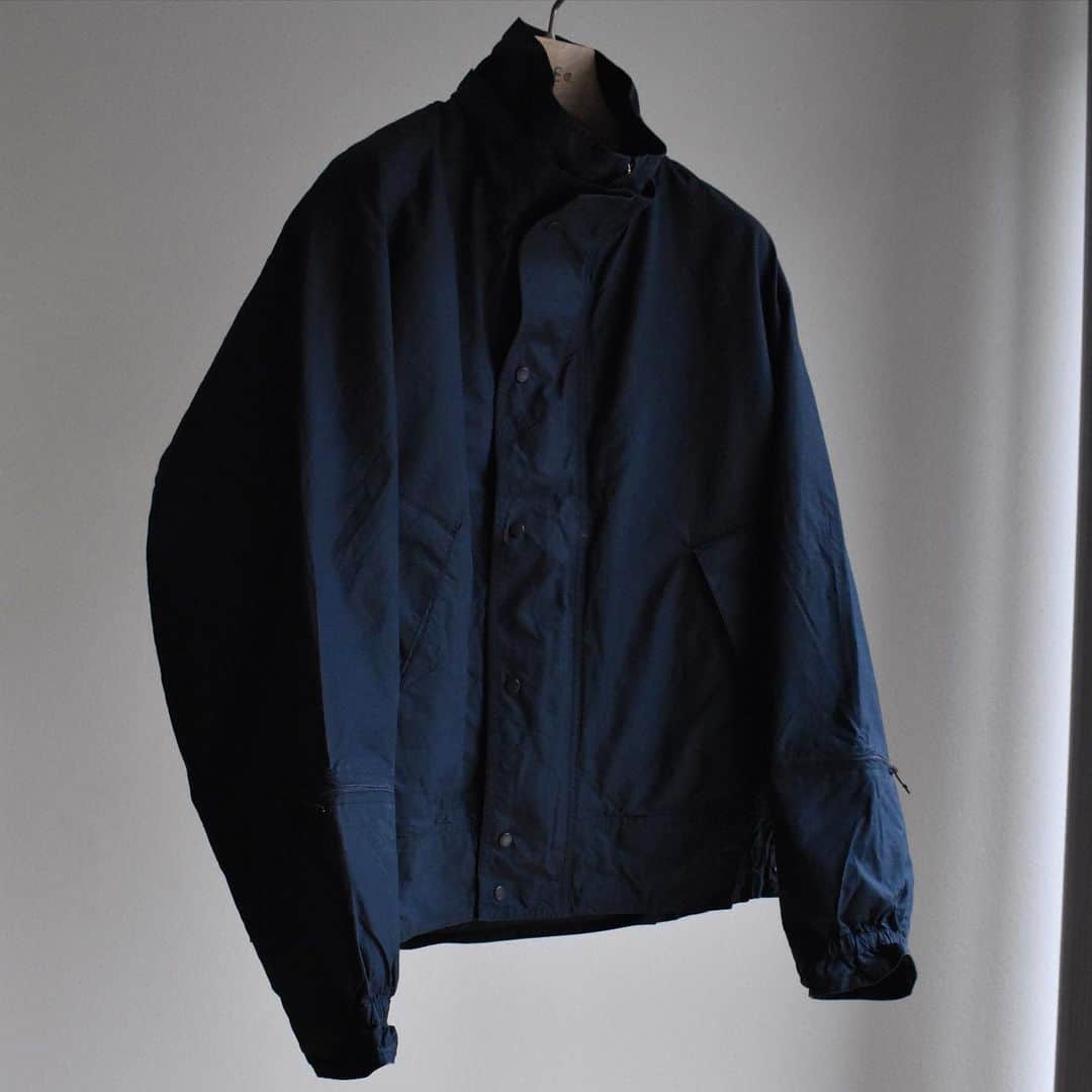 キャプテン サンシャインのインスタグラム：「﻿ "Portage Blouson"﻿ ﻿ Light Beige / Navy﻿ ﻿ 先染のエジプト超長綿を限界まで打ち込み、仕上げた高密度オックスフォード素材。﻿ 着脱フードや袖のジップポケット﻿ などミリタリー要素を取り入れながら、コットン素材を無双仕立てにすることで、独特な丸みと柔らかい表情に仕上げました。﻿ 製品洗い、撥水加工を施しています。﻿ ﻿ #kaptainsunshine ﻿ #21ss」
