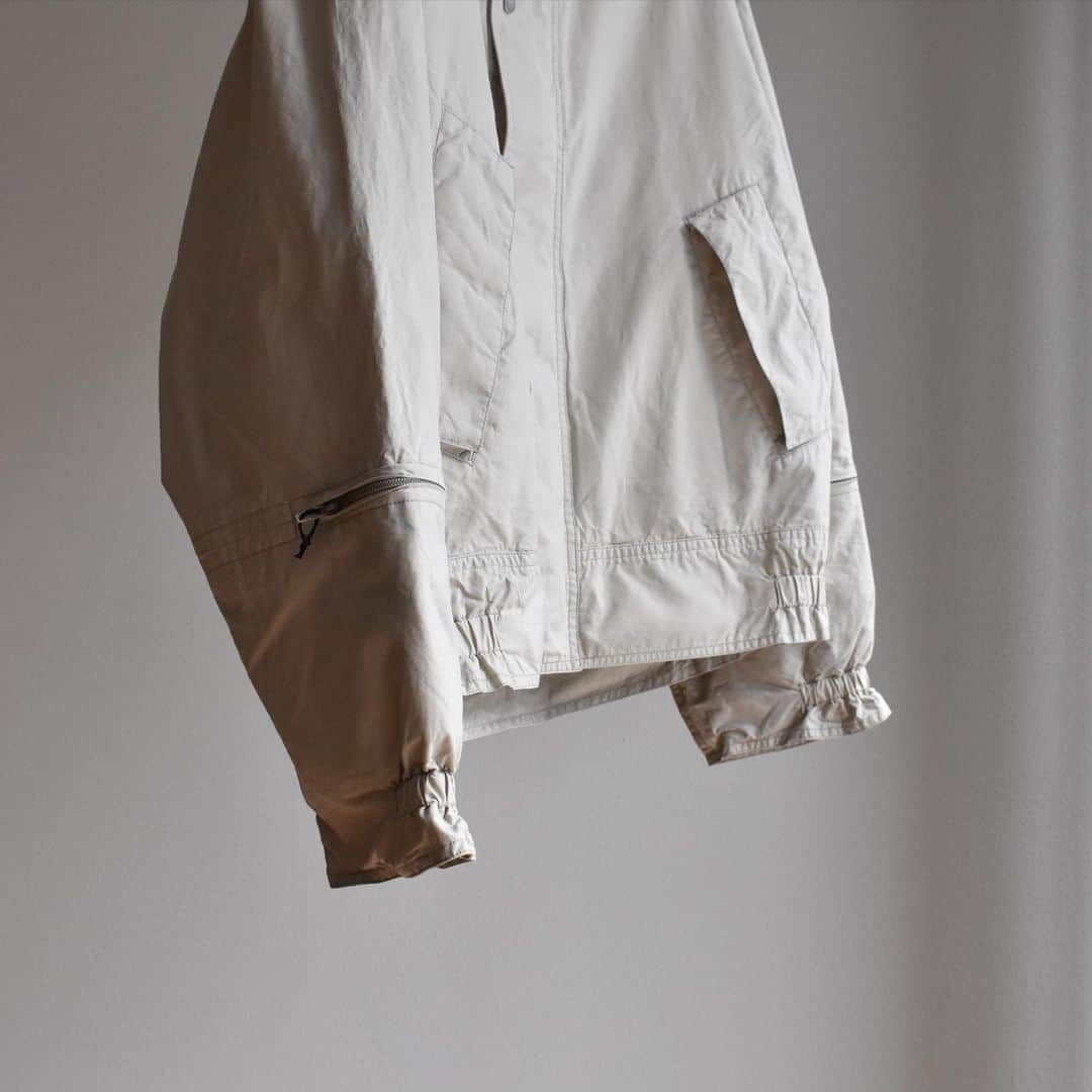 キャプテン サンシャインのインスタグラム：「﻿ "Portage Blouson"﻿ ﻿ Light Beige / Navy﻿ ﻿ 先染のエジプト超長綿を限界まで打ち込み、仕上げた高密度オックスフォード素材。﻿ 着脱フードや袖のジップポケット﻿ などミリタリー要素を取り入れながら、コットン素材を無双仕立てにすることで、独特な丸みと柔らかい表情に仕上げました。﻿ 製品洗い、撥水加工を施しています。﻿ ﻿ #kaptainsunshine ﻿ #21ss」