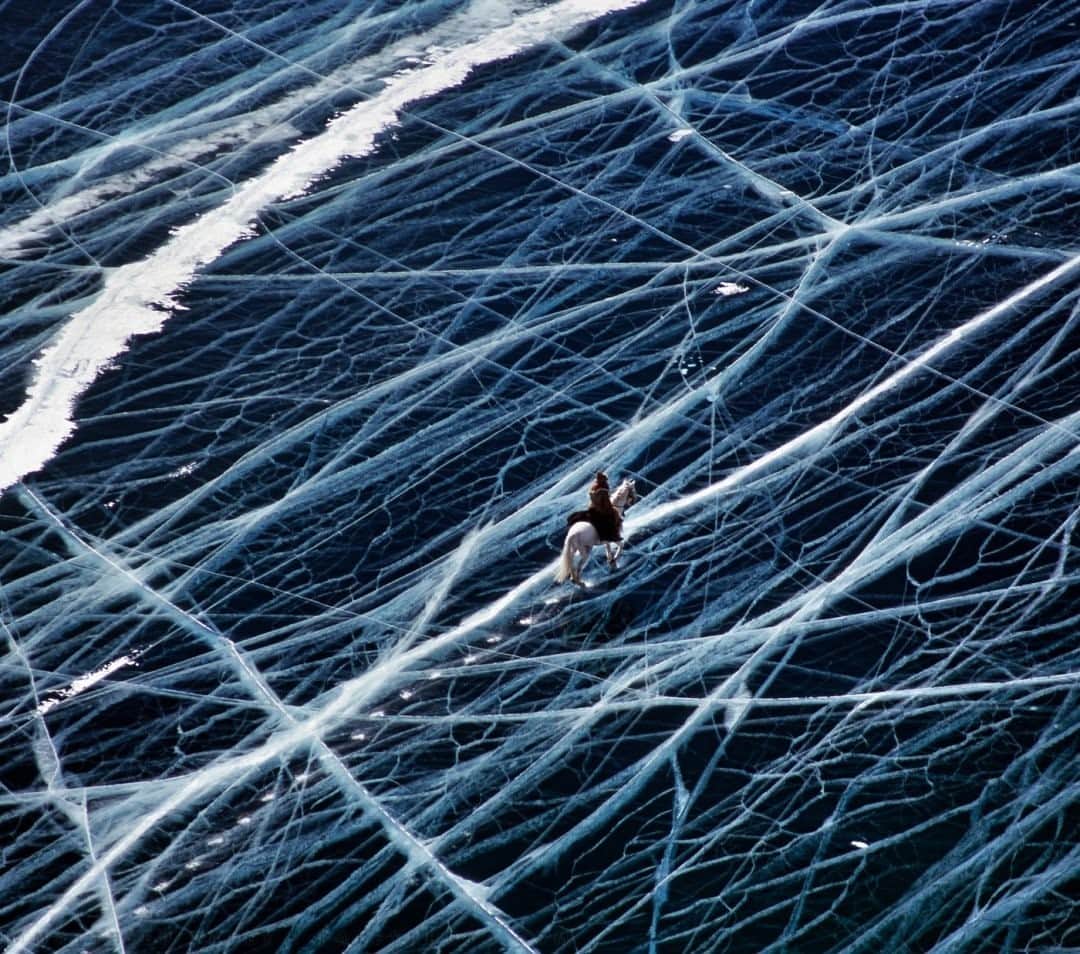 ナショナルジオグラフィックさんのインスタグラム写真 - (ナショナルジオグラフィックInstagram)「Photo by Matthieu Paley @paleyphoto / I have heard many interpretations of this image. It’s often thought to be a macro shot of a nervous system. In fact, I only had to climb a cliff to get this bird’s-eye view of a horseman riding in the middle of winter on Lake Baikal in Siberia. And even though the ice is cracked, it is over a meter thick, and even trucks drive across the lake in this season. There is much water under the spiked hooves of that horse—Lake Baikal is the world’s largest freshwater lake by volume, containing over 20 percent of the world’s liquid fresh surface water and up to a mind-boggling 1,642 meters (5,387 feet) deep. For more cultural insights into our world, follow @paleyphoto. #lakebaikal #crackedice #ice #frozenlandscape」2月1日 2時33分 - natgeo