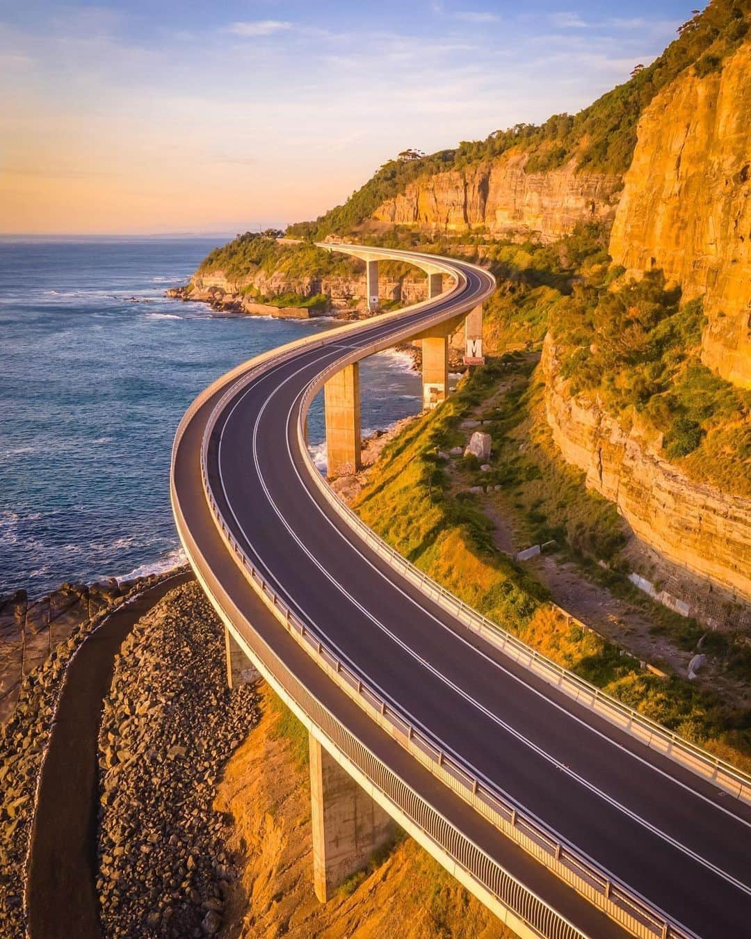Australiaさんのインスタグラム写真 - (AustraliaInstagram)「Sunrise on the #SeaCliffBridge, perfectly captured by @itsdavesdrone ☀️ This impressive bridge is part of the #GrandPacificDrive, a wonderfully scenic road trip along the coast of @visitnsw. Ready to hit the road? Depart @sydney for a day of delicious food and Insta-worthy views like this one. Some key stops are the quaint seaside towns of Thirroul and Austinmer (get a coffee at @breadespressoandthirroul), @visitwollongong for top surf and burgers at @his_boy_elroy, and the iconic #blowholes at #Kiama followed by dinner at @pennywhistlers. Want to follow the #GrandPacificDrive yourself? Head to the link in our bio to find out more. #seeaustralia #ilovesydney #LoveNSW #HolidayHereThisYear」1月31日 19時00分 - australia