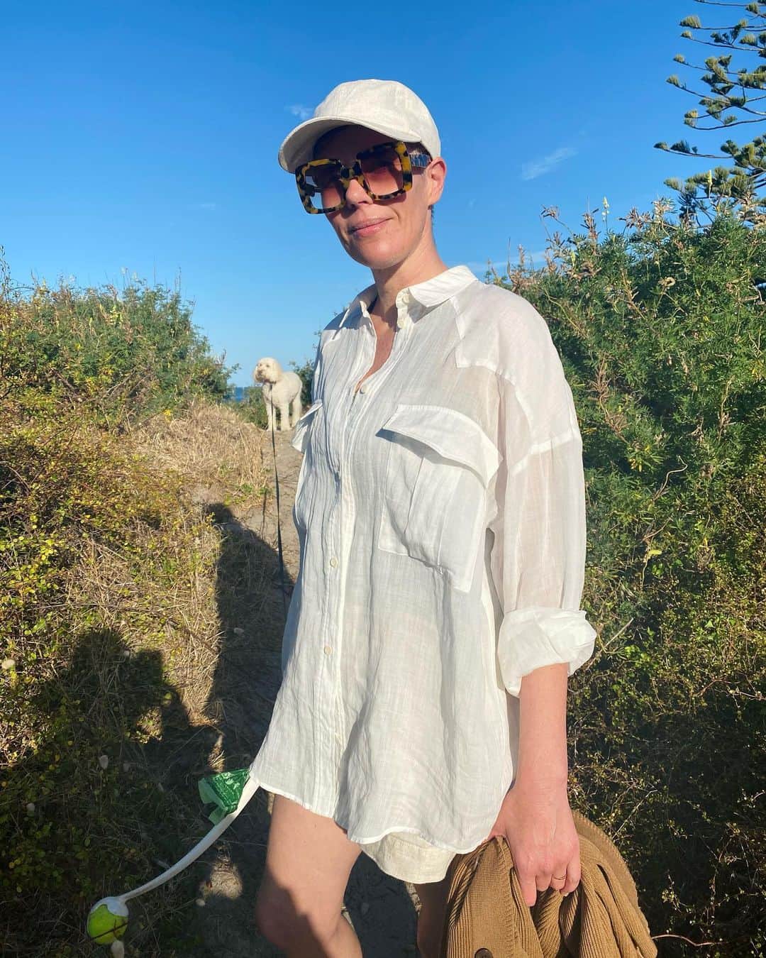 カレンウォーカーのインスタグラム：「Karen wears the ‘Gentleman Shirt’, equally great for beach and work. Laika waits patiently.. 🎾 As with all our organic cotton pieces, made by our @fairtradecertified partners in India.」