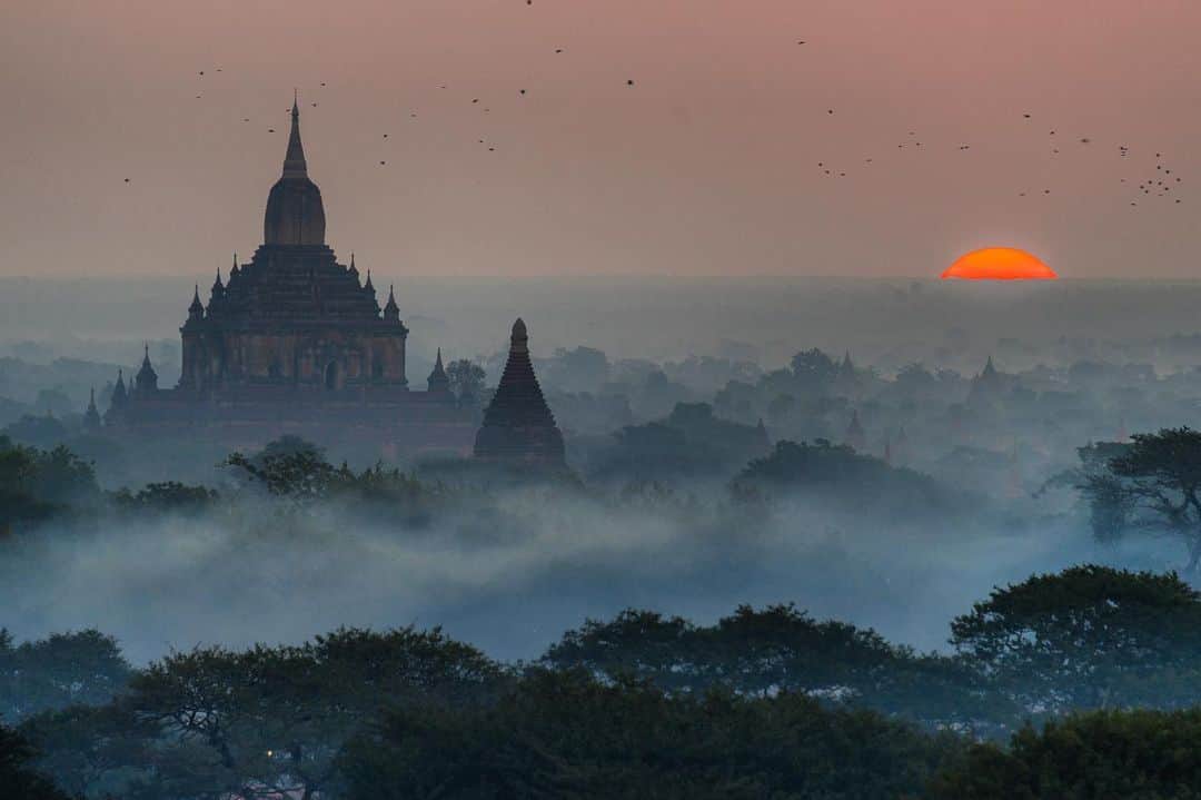 Michael Yamashitaのインスタグラム：「A troubling new dawn in Myanmar: Bagan is an ancient city and a UNESCO World Heritage Site, and since 2011, one of Myanmar's most popular tourist and pilgrimage sites. From the 9th to 13th centuries, the city was the capital of the Pagan Kingdom that unified the regions that would later constitute Myanmar. During the kingdom's height between the 11th and 13th centuries, more than 10,000 Buddhist temples and pagodas were constructed in the Bagan plains alone, of which the remains of over 2200 temples and pagodas survive. "Temples of gold” is how Marco Polo described them in his Travels of Marco Polo -- “… and when they are lighted up by the sun they shine most brilliantly and are visible from a vast distance.” The age and majesty of these gold-plated temples are reminders that despite current troubling political upheavals, Myanmar is an ancient land that has prevailed throughout ever-shifting alliances and wars for hundreds of years. #bagan #myanmar #bagansunrise #worldheritage @thesilkroadjourney」