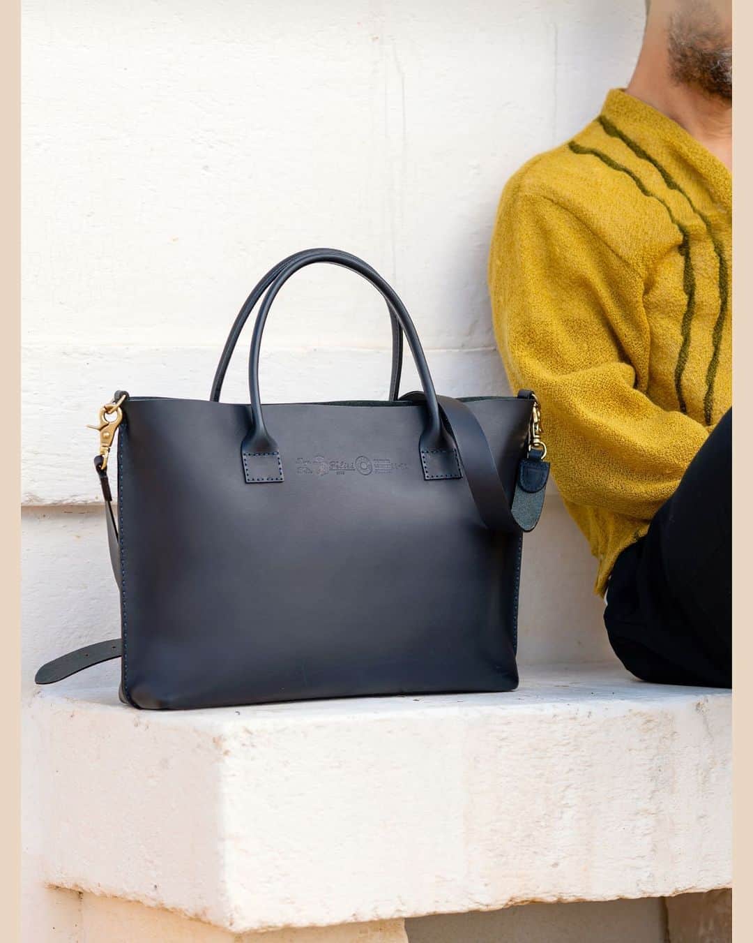 Felisi Japan 〔フェリージ〕のインスタグラム：「【2021 SPRING & SUMMER COLLECTION】 . ■SUSTAINABILITY LINE –PUNTO A MANO- . 創業当時のフェリージは、全行程を手縫いで行い、 ノンケミカルで製造されたレザーを使用していました。 「Punto a mano」はそんなフェリージの原点に立ち返って、 次の未来を見つめるモデルと言えます。 フェリージを象徴するバケッタレザーをサスィテナブルな方法でつくり、 そのレザーで一生モノのバッグをつくる。 洒脱で、軽快で、でも揺るがないフェリージの信念を、 このバッグから感じ取ってください。 . Model No. 21/28/A Price : ¥119,900 . . ▶詳しくはプロフィールページからもご覧いただけます。 . . . #felisi #felisiselection #felisicollection #SS21 #newcollection #sustainability #puntoamano #leatherbag #vachettaleather #totebag #bag #フェリージ #フェリージセレクション #フェリージコレクション #2021年春夏 #新作コレクション #サスティナビリティ #プントアマーノ #バケッタレザー #レザーバッグ #レザートート #トートバッグ #バッグ #かばん #鞄」