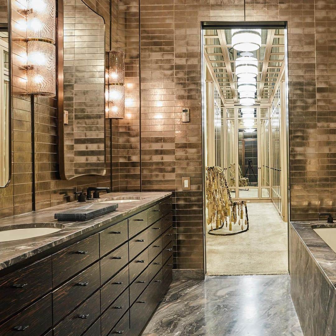 ケリーウェアスラーのインスタグラム：「MIXED MEDIA. An ode to natural materials drove the design of the master bath for my clients’ New York abode. Floors, bath tub and countertops are lined with an incredible rare cut of marble. We covered walls in these luminescent glass tiles to cherish the glow emanating from vintage sconces. XK」