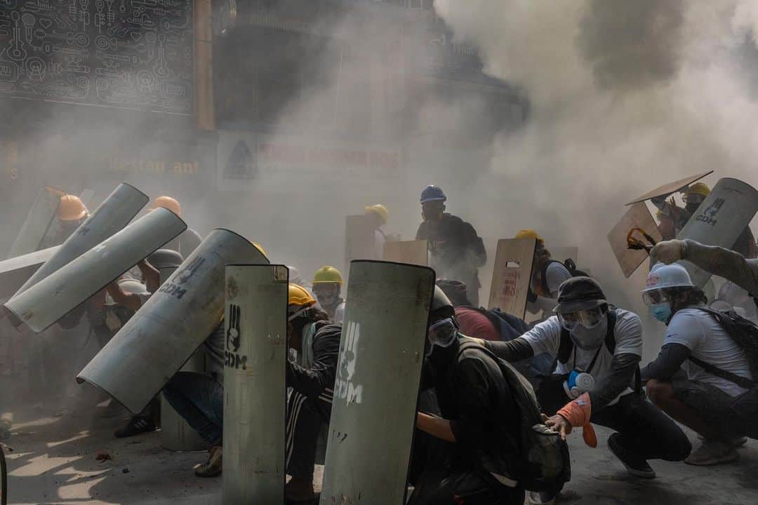 TIME Magazineのインスタグラム：「At least 18 people were killed in Myanmar on Feb. 28 after security forces opened fire on crowds peacefully demonstrating against the military takeover, @apnews reports, citing the @unitednations. Deaths were reported in Yangon, the country's largest city, as well as Dawei, Mandalay, Myeik, Bago and Pokokku. U.N. Secretary-General António Guterres "strongly" condemned the crackdown in a statement, calling the use of lethal force against peaceful protesters "unacceptable" and urging the international community to "come together and send a clear signal to the military that it must respect the will of the people of Myanmar as expressed through the election and stop the repression." In these photographs: protesters defend themselves in Yangon; a protester washes his face after riot police fired tear gas; a protester uses a makeshift shield as people watch from a nearby building; and a protester who was injured after being shot at with live rounds is transported to a makeshift medical center in Mandalay. Photographs by @hkun_lat—@gettyimages and Stringer—@afpphoto/@gettyimages」