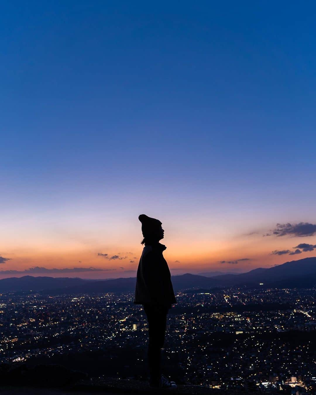 詩歩さんのインスタグラム写真 - (詩歩Instagram)「Magic hour in Kyoto🌙  三方を山に囲まれた京都。 中でも「五山の送り火」で有名な「大文字山」は気軽に登れる山として人気なんです🔥  「いつか登ろう」と思いながらも、一人で登るのもな〜、夏は暑いしな〜、冬は寒いしな〜と機会を逃していたのですがｗ、偶然マジックアワーを見るガイドツアーがあるのを発見したので登ってきました🥾  登山の開始は、なんと銀閣寺😳 銀閣寺の参道脇が登山道になっているので、そこから標高466mの大文字山（如意ヶ岳）山頂を目指します。  散歩がてら登る人もいるくらいなので30分ちょいでサクッと登れる山。でも今回は暗くなりかけてから登り始めたのでけっこう怖かった…懐中電灯必須🔦（ちなみに私が参加した日は平日だったので貸し切りでした✌）  写真は、五山の送り火の「大」の字が実際に燃やされる「火床」からの眺望。京都市内が一望できて本当に気持ちよかった〜✨（ここは山頂ではない）  写真はガイドさんにお願いして撮ってもらいました📸♡  緊急事態宣言も明けたので住民としては人出が急増しないかヒヤヒヤしていますが、あえて京都でアウトドアってのもいかがですか？  🥾  Kyoto is surrounded by mountains on three sides, and Daimonjiyama, famous for the Gozan-no-Okuribi (Bonfire of the Five Mountains) in summer, is one of the most popular mountains to climb in Kyoto. 🔥  I've always wanted to climb it, but I've never had the chance, because it's too hot in summer and too cold in winter. But by chance I found a guided tour to see the magic hour, so I joined!  We started climbing at Ginkakuji Temple.There is a hiking trail beside the approach to Ginkakuji Temple, from where you can reach the summit of Daimonji Mountain (Nyoigatake), which is 466m above sea level.  It's a mountain that some people climb on a walk, so you can climb it quickly in a little over 30 minutes. The photo shows the view from the fire pit where the character for "big" in Gozan-no-Okuribi is actually burned. It was really nice to see the whole city of Kyoto ✨.(This is not the top of the mountain.) Why not venture outdoors in Kyoto? 📷  #shiho_kyoto 📍大文字山トレッキング／京都 📍Mt.Daimonji-yama trekking ／Kyoto  ©詩歩 / Shiho」3月1日 17時27分 - shiho_zekkei