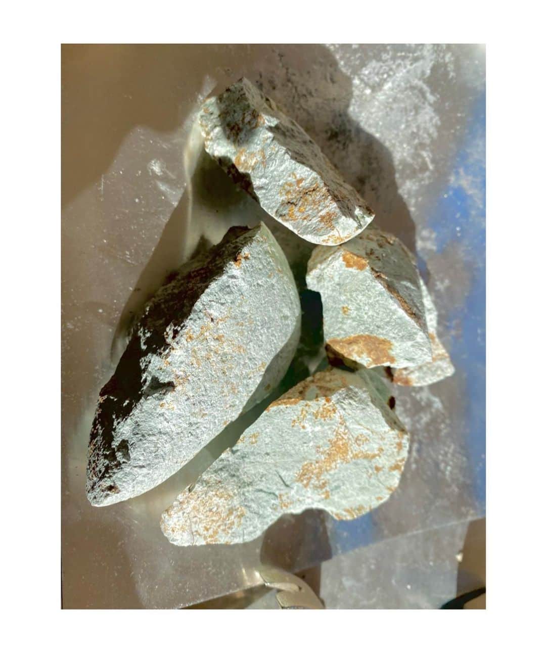 のインスタグラム：「Material research ： Riverside minerals  _ 征く先々で採集した鉱物。 それを粉砕し、粉状にします。それから膠を使って混ぜ合わせ、岩絵具を作成。支持体（紙や布）との整合性、親和性を探りながら、自然との深い関わりから何が生まれるのか。ー　 天然の鉱物ゆえに予期しない範囲へと色や質感は向かい、自分と自然との間に存在する“何か“を可視化します。  時間を見つけるとすぐに東京を飛び出し、自然界へ赴くことが日課である私は日本の様々な土地を旅をしてきた。景色を眺め、一息つくのが主な目的であり、大概のことはそれでリフレッシュされる。自然の恩恵をたくさんもらってきた中で、人間（自分）と自然との関係性や緊張感、そこに在る空気のようなものをメッセージとして生み出したいと考えました。 採集した3種類の鉱物はそれぞれ標高、地形の違いを意識し、標高が比較的高い火山跡の土地では赤茶のもの、丘の続く土地から黒ずんだ青緑、下流の河原に流れ着いていた薄緑の鉱物を対象に。異なる地形や標高、存在していた環境によって密度の違いがあり、硬さや色の出方は様々になります。これら鉱物から色味を抽出し、現象に近しい状態で支持体へアプローチ。その'何か'について発見することを目的として制作をしています。」
