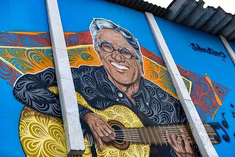 カエターノ・ヴェローゾのインスタグラム：「Fico muito orgulhoso de ver minha cara na parede do clube de Guadalupe. Tenho muito orgulho de ser ligado a esse bairro do Rio. Me sinto um carioca (na medida em que me sinto carioca) de lá.  Cito Guadalupe na música “Pé do Meu Samba”, que fiz para @tnalia. Também na canção "Meu Rio" há o verso: "Guadalupe em mim é Fundação". E "Perto da favela do Muquiço". (Link para ouvir nos stories)  Grafite: @julianafervo   #CaetanoVeloso #Guadalupe」