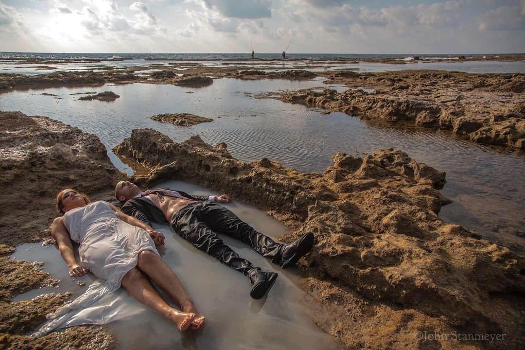 ジョン・スタンメイヤーさんのインスタグラム写真 - (ジョン・スタンメイヤーInstagram)「Sometimes the universe brings the unexpected. One such occurrence was in northern Israel outside Haifa, more specifically, Akko (Acre). Bored by what I was photographing while walking along the Mediterranean Sea, Ayla and her fiancé, Maor, appeared out of nowhere. Together laying in the shallows of a rocky shoreline, wearing a dress and suit. Were it not for their photographer, Lior Marzada, photographing portraits from a distance of the soon-to-be-married couple, I would have imagined they fell out from the sky. Once in a while, you can be at a most simple place and come across the strangest things. ⠀⠀⠀⠀⠀⠀⠀ from the @natgeo story #BlessedCursedClaimed #fromthearchives #israel #akko #acre #beach #mediterraneansea #bride #groom #dress #suit #falloutfromthesky」2月12日 12時43分 - johnstanmeyer