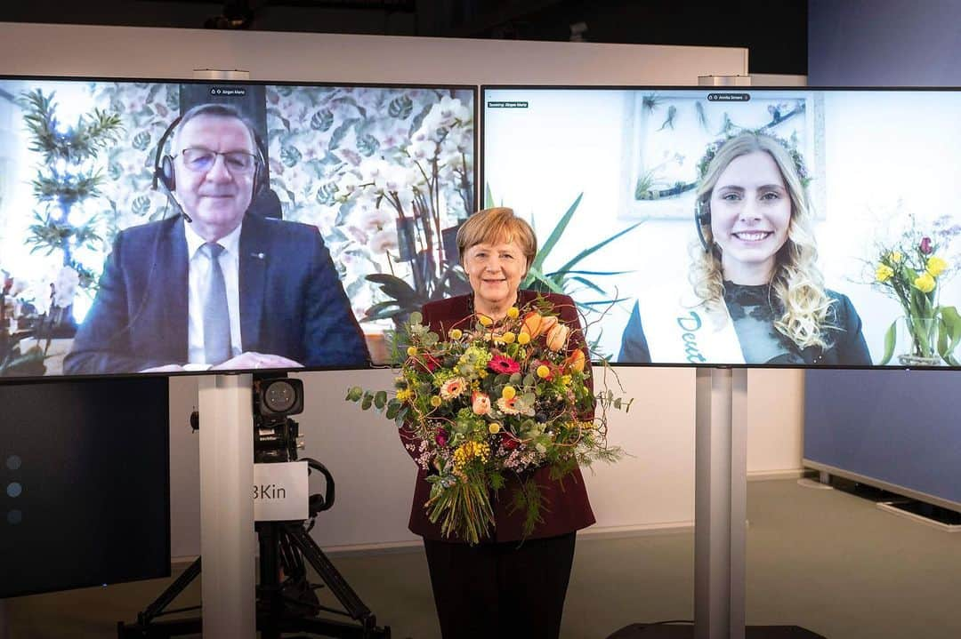 アンゲラ・メルケルのインスタグラム：「Eine etwas andere Übergabe: Kanzlerin Merkel nimmt einen Blumengruß anlässlich des Valentinstags 2021 von der Deutschen Blumenfee und einem Vertreter des Zentralverbandes Gartenbau in Empfang. Wegen der Corona-Pandemie ist die Übergabe in diesem Jahr virtuell. --- A somewhat different handover: Chancellor Merkel receives a flower greeting on the occasion of Valentine's Day 2021 from the German Flower Fairy and a representative of the Central Horticultural Association. Due to the Corona pandemic, the handover is virtual this year. . . . #Bundeskanzlerin #Merkel #Blumen #Bundeskanzleramt #Blumenfee #Valentinstag2021 #Politik」