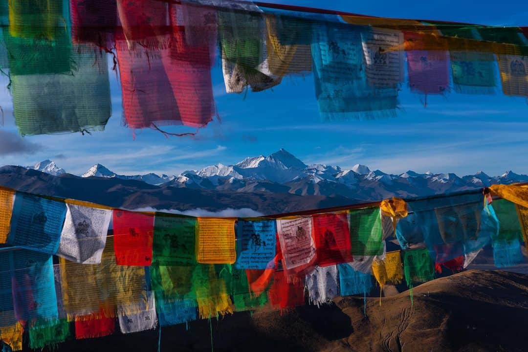 のインスタグラム：「Tashi Delek! Celebrating the third day of Losar, the Tibetan New Year, with this classic view of Mount Everest, adorned by the ubiquitous prayer flags. The world’s tallest (8800m) mountain flanked by its 5 neighboring peaks, all over 8000m, known as the roof of the world. Its Tibetan name is Holy Mother or #Chomolungma #tashidelek #everest #losar #mounteverest #prayerflags #tibet」