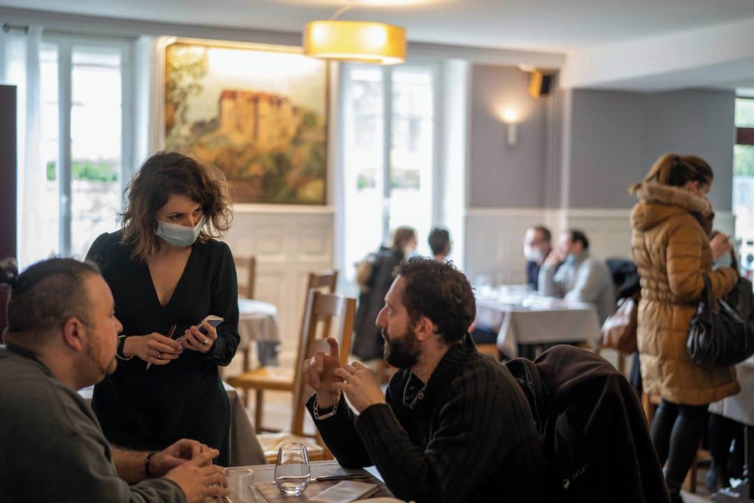 ルモンドのインスタグラム：「Depuis le trottoir de la rue du 11-Novembre, axe principal de la commune de Boussac (Creuse), des silhouettes attablées se dessinent derrière les fenêtres de l’hôtel-restaurant Le Central, jeudi midi. Dans la salle, à la décoration rustique mais épurée, 25 clients déjeunent. Quatre par table au maximum, et un mètre de distance entre les chaises, selon le protocole sanitaire renforcé.⁣ Le département est le premier à avoir permis le retour, dès le 4 janvier, des ouvriers et employés des travaux publics dans les restaurants, à l’initiative de la chambre de commerce et d’industrie (CCI) de la Creuse. Sur les 485 établissements du département, 45 ont signé une convention. Un contrat doit également être passé entre les restaurants et chaque entreprise reçue.⁣ Jérôme et Lise-Marie Menu, propriétaires du Central, n’ont jamais complètement fermé leur cuisine. Mais depuis la dérogation celle-ci a retrouvé son animation, comme ce jeudi : Aboubakar Kebe et Antoine Preuvot, les apprentis, et le second de cuisine, Jonathan Bonnat, sont de retour au restaurant. C’est pour eux que le patron participe à l’opération : « Pour le moral de mon cuisinier et la formation de mes deux apprentis, mais pas pour le chiffre d’affaires, presque inchangé ». Et puis aussi, dit-il, « pour notre propre moral : parce que voir son restaurant vide, c’est dur ».⁣ -⁣ 1 : Lise Menu, gérante, prend les commandes en salle, au Central, à Boussac (Creuse), le 11 février 2021⁣ 2 : L'hôtel-restaurant Le Central, à Boussac (Creuse)⁣ 3 : Des clients arrivent pour le service de midi⁣ 4 : Pause déjeuner pour Daniel, Ibrahim, Thierry et Hugo qui travaillent sur un chantier à quelques kilomètres du restaurant⁣ 5-6-7 : Aboubakar Kebe et Antoine Preuvot, les apprentis, et le second de cuisine, Jonathan Bonnat, travaillent pour le service en salle et la vente à emporter⁣ 8 : Au restaurant Le Central, à Boussac (Creuse)⁣ -⁣ Photos : Samuel Gratacap (@samuelgratacap) #PourLeMonde⁣ -⁣ #restaurant #covid #Creuse #Boussac」