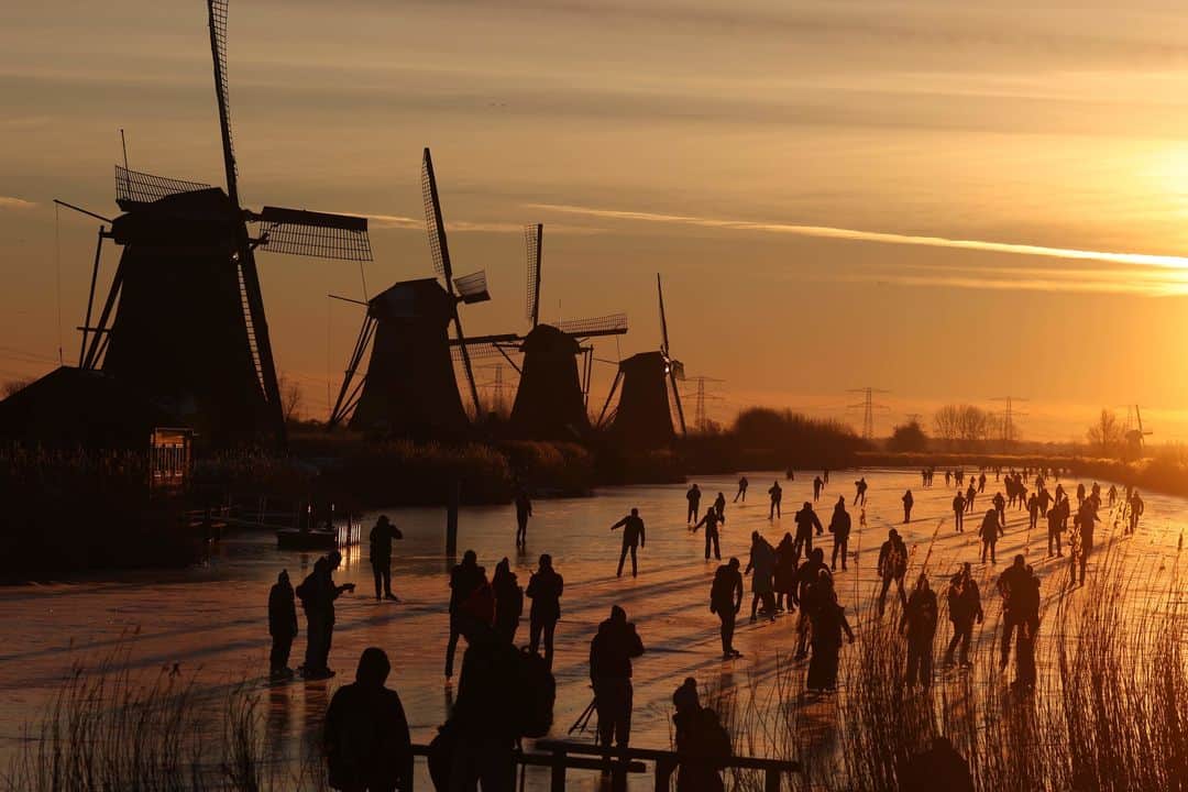 ルモンドのインスタグラム：「Les Néerlandais ont de nouveau sorti leurs patins à glace dimanche pour profiter du dernier jour d'un froid persistant, comme à Kinderdijk (ouest), près des emblématiques moulins à vent inscrits au patrimoine mondial par l'Unesco, où plusieurs dizaines de personnes patinaient déjà tôt dimanche matin.⁣ Malheureusement, la hausse des températures après une semaine de froid glacial, couplée aux restrictions liées à la crise sanitaire, ont douché les espoirs de pouvoir organiser, pour la première fois depuis 1997, une course mythique de patinage de vitesse: l'Elfstedentocht (Tour des onze villes), qui voit s’affronter les meilleurs patineurs sur un parcours de près de 200 kilomètres sur les canaux, rivières et lacs gelés de la province de Frise.⁣ Le dernier vainqueur de cette course très populaire aux Pays-Bas, maintenant âgé de 53 ans, a toutefois tenté de parcourir cette année le tracé de l’épreuve en profitant de la vague de froid mais n'a pas pu arriver au bout de l'itinéraire, notamment à cause d'une "mauvaise glace" et d'un temps limité par le couvre-feu en vigueur.⁣ -⁣ Des patineurs de sortie sur un canal gelé à Kinderdijk, aux Pays-Bas, le 14 février. Photo : Kenzo Tribouillard (@kenzo.tribouillard) / AFP (@afpphoto)⁣ -⁣ #patinaglace #Elfstedentocht #PaysBas #sport」