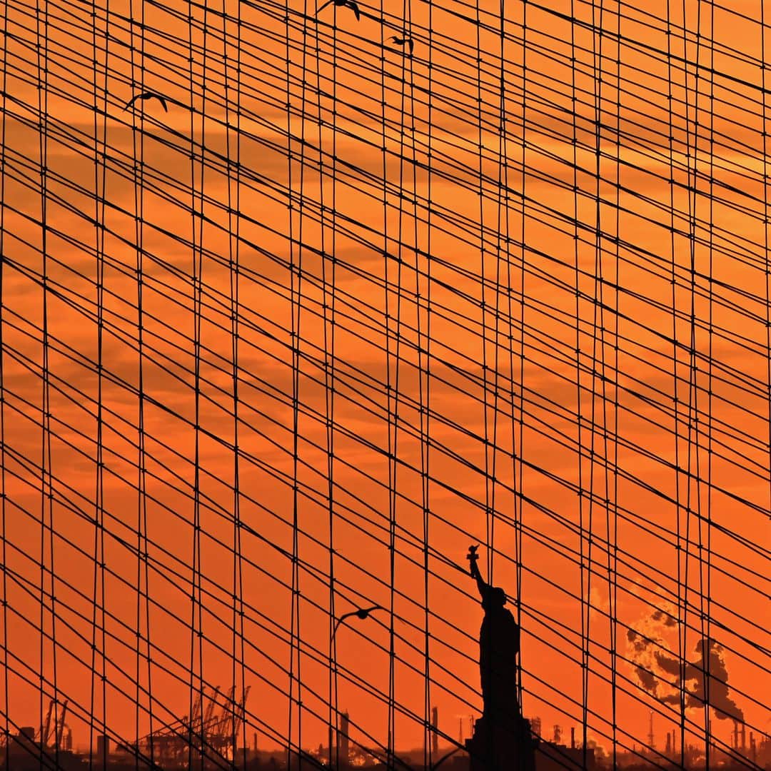 AFP通信さんのインスタグラム写真 - (AFP通信Instagram)「AFP Photo 📷 @angelaweissphoto - The Statue of Liberty is seen at sunset through the steel-wire suspension cables of the Brooklyn Bridge on February 17, 2021 in New York City.」2月19日 2時37分 - afpphoto