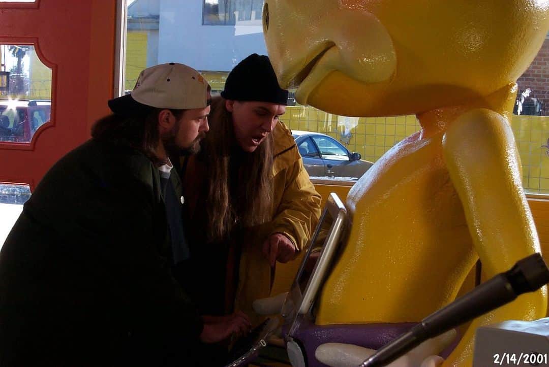 ケヴィン・スミスのインスタグラム：「Wanna feel old? 20 years ago (on Valentines Day), @jaymewes yelled “YOU ARE THE ONES WHO ARE THE BALL-LICKERS!” for the first time as we shot the #moobys scene in @jayandsilentbob Strike Back! And 20 years later, here’s me announcing that after a successful week-long run at @thevanburenphx, the next @moobyspopup is going to be in ORLANDO! That’s right: our authentic fake fast food golden calf is gonna set up shop in a section of FLORIDA not normally known for themed entertainment! But the real upside is that this trip will afford me the first opportunity to see my Mom in many months (@donsgirlgrace will cut the ribbon on opening day)! Tickets go on sale next week, so sign up for info at the link in my bio above! Very crazy to think that what was once a fictional eatery has now been made flesh IRL in L.A., Red Bank, Chicago, Toronto, Minneapolis, and Phoenix, with Vancouver and Florida to follow! And since @heyitsderekberry has more #moobys booked across the country through September, #jasonmewes and I might soon pop up in a city near *you*! But back in 2001, with zero inkling we’d one day be able to eat a @beyondmeat CowTipper, we were all about the Internet. I remember getting a note that all the talk about the Internet and online culture was too “inside” for a mainstream audience. Little did we know the world would more closely resemble this scene today than it did when we actually shot it. Back then, it was considered comedy to show a scene of some crackpot spewing vitriol online. Nowadays, it’s a daily drama. So I suggest we save all the drama for our Mommas and meet at Mooby’s in Orlando! (Location and dates will be announced next week!) Amazing Orlando Art by @thedarknatereturns! #KevinSmith #jasonmewes #moobys #jayandsilentbobstrikeback #food #jaymewes #moobyspopup #orlando #florida #whatthefuckistheinternet」