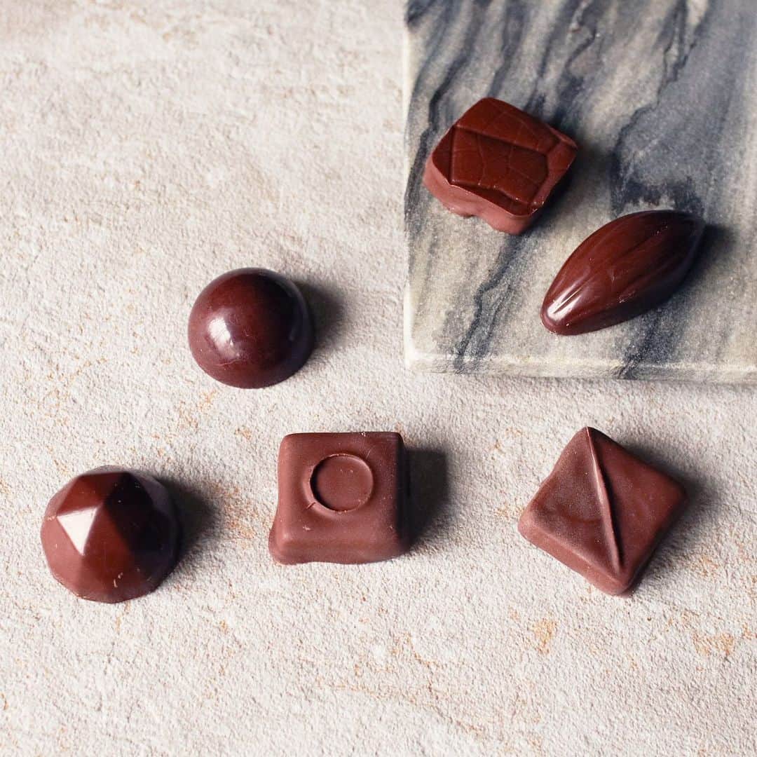 ダンデライオン・チョコレート・ジャパンさんのインスタグラム写真 - (ダンデライオン・チョコレート・ジャパンInstagram)「■チョコレートの正しい保存方法は？おいしさを保つためのコツ Part 1﻿ ﻿ ﻿ チョコレートは傷みにくい食品ではあるものの、温度変化の影響を受けやすく、保存方法には注意する必要があります。しかし、チョコレートの適切な保存方法は、実はあまり知られていません。﻿ そのため、保存しておいたチョコレートを食べようとしたら、白っぽくなったり、ボソボソした食感になったり、風味が大きく落ちてしまったりした…なんて経験はありませんか？﻿ ﻿ ここでは、チョコレート本来のおいしさを保つための基本の保存方法をご紹介いたします。﻿  -------------------------------------------------﻿ チョコレートを保存する前に、賞味期限を確認しよう﻿ ------------------------------------------------- チョコレートを保存する際は、まずそのチョコレートの賞味期限と保存方法を確認するのがポイントです。﻿ ﻿ 賞味期限は、そのチョコレートを安心して食べられる期間のことで、チョコレートの種類によって変わってきます。特に、生クリームなどを使用した水分量の多いタイプは賞味期限が短いため、保存期間にも注意が必要です。中には、数日しか持たないものもあります。﻿ チョコレートの賞味期限や保存方法については、パッケージなどに記載されています。﻿ ﻿ ------------------------------- 種類別・チョコレートの保存方法﻿ ------------------------------- 保存方法もチョコレートの種類によって異なります。﻿ 「一般的なチョコレートチョコレートバー（板チョコレート）」「ガナッシュチョコレート」「ボンボンショコラ」の3つのタイプ別に見ていきたいと思います。﻿ ﻿ ▶︎一般的なチョコレートやチョコレートバー（板チョコレート）の場合﻿ チョコレートバーなどの一般的なチョコレートは、22℃以下を目安に保存するのがおすすめです。夏場を除けば、常温保存でも問題ないかと思います。ただ、暖房などによって室温が上がる場合は、お気をつけください。﻿ また、直射日光や湿気もチョコレートを劣化させる原因となるため、高温多湿を避けられる場所に保存しましょう。﻿ もし、ワインセラーがご自宅にあるようでしたら、そこに保存すると最適な環境をキープしていただけます。﻿ ﻿ ▶︎生チョコレート・ガナッシュの場合﻿ 生チョコレートとは、溶かしたチョコレートに生クリームを合わせ、冷やし固めたものです。ケーキのデコレーションに使われたり、トリュフやフォンダンショコラの中に入っていたりする「ガナッシュ」は、生チョコレートを冷やし固める前の、ゆるい状態のものを指します。﻿ 生クリームが含まれていることから、生チョコレートやガナッシュは長期保存には不向きです。そのため、保存する際には、必ず賞味期限をご確認ください。10℃以下での保存が望ましく、シーズンを問わず冷蔵庫で保存するようにしてください。﻿ ﻿ ▶︎ボンボンショコラの場合﻿ 果汁やアーモンド、ウイスキーなどを包んだ、トリュフのような一口サイズのチョコレートが、ボンボンショコラです。こちらは、16℃以下を目安に保存します。﻿ 季節によっては、室温でも問題ないと思います。﻿ ﻿ ﻿ ﻿ #dandelionchocolate﻿ #ダンデライオン チョコレート﻿ #beentobar﻿ #ビーントゥバー﻿ #craftchocolate﻿ #クラフトチョコレート﻿ #chocolate﻿ #チョコレート﻿ #cacao﻿ #カカオ﻿ #チョコレートの保存方法﻿ #保存方法﻿ #基本の保存方法」2月19日 14時46分 - dandelion_chocolate_japan