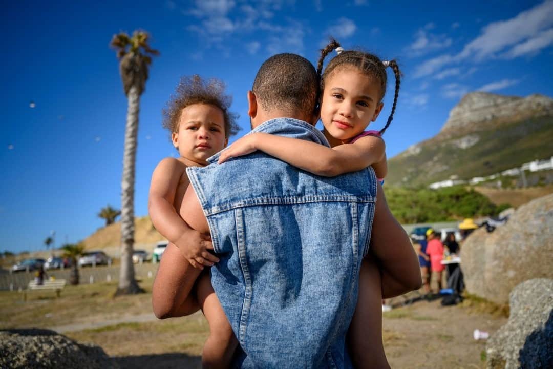 National Geographic Travelさんのインスタグラム写真 - (National Geographic TravelInstagram)「Photo by @amivitale / A father carries his two daughters along the beach in Cape Town, South Africa. Despite the water's chilly temperatures, the beach is still a focal point for both locals and tourists.  Follow @amivitale for more stories about our connections to one another around the world. @thephotosociety #southafrica #capetown #africa」2月20日 12時34分 - natgeotravel