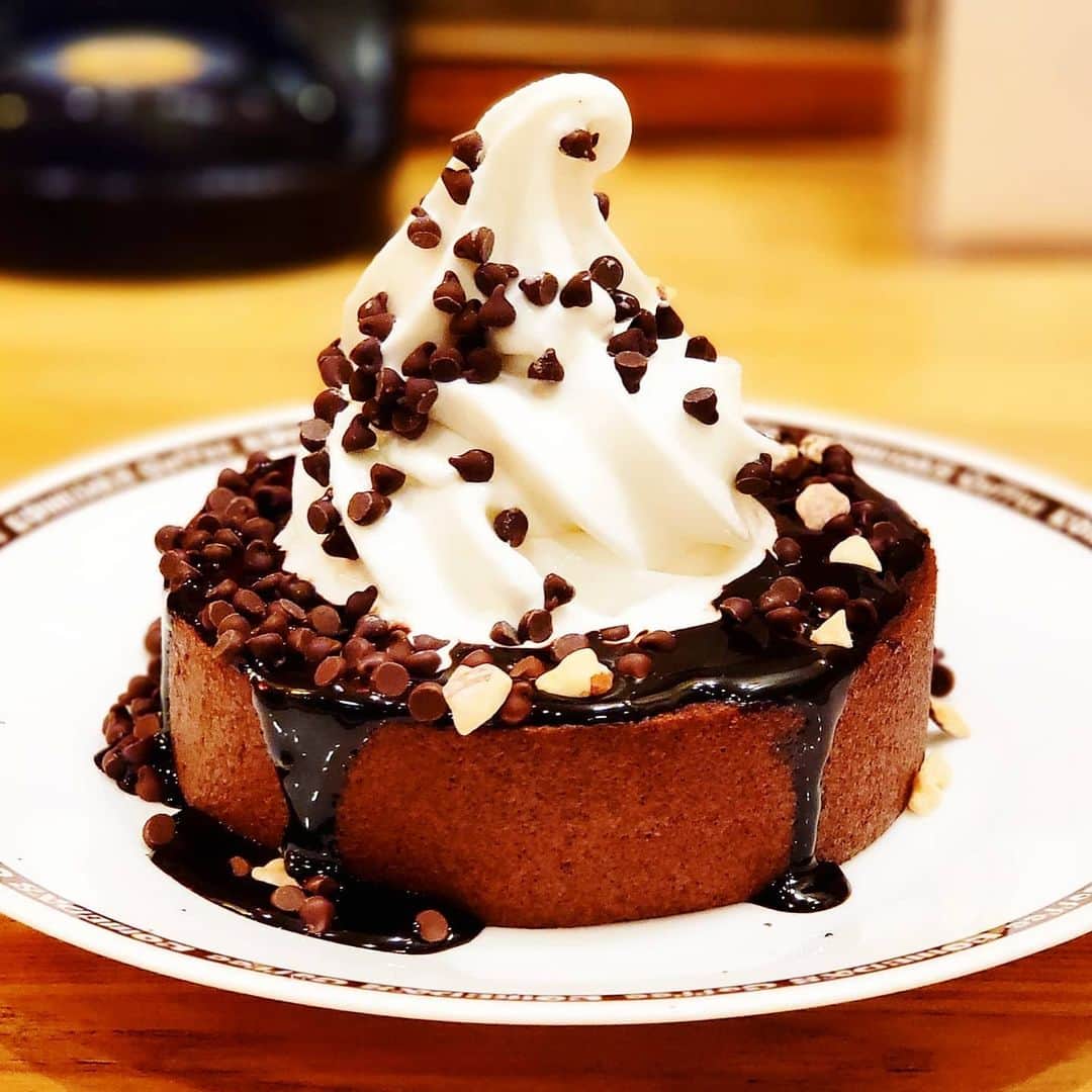 のインスタグラム：「ここここコメダ！ 【コメダ珈琲店】 2/5～限定数に達し次第終了 GODIVA ✕ コメダ珈琲店 コラボ 🍫クロネージュ リッチショコラ  GODIVAのエグゼクティブ シェフ・ショコラティエ監修の“コメダ史上最強スイーツ”ともされる限定コラボメニューが登場中  ベルギー産カカオを使用した、チョコレートバウムクーヘンの表面を艷やかなチョコレートソースでグラサージュ TOPにソフトクリームを盛り、さらに散らしたチップチョコ、アーモンドプラリネが良いアクセントになり、大満足な美味しさにゃー😸  🚶1部店舗を除く全国の「コメダ珈琲店」で発売中 限定数達した店舗から順次終了 詳しくはコメダ珈琲店SNSを @komeda_coffee_official  #黒猫食べ過ぎ #ゴディバ #GODIVA #コメダ珈琲店 #コメダ珈琲 #黒猫北千住」