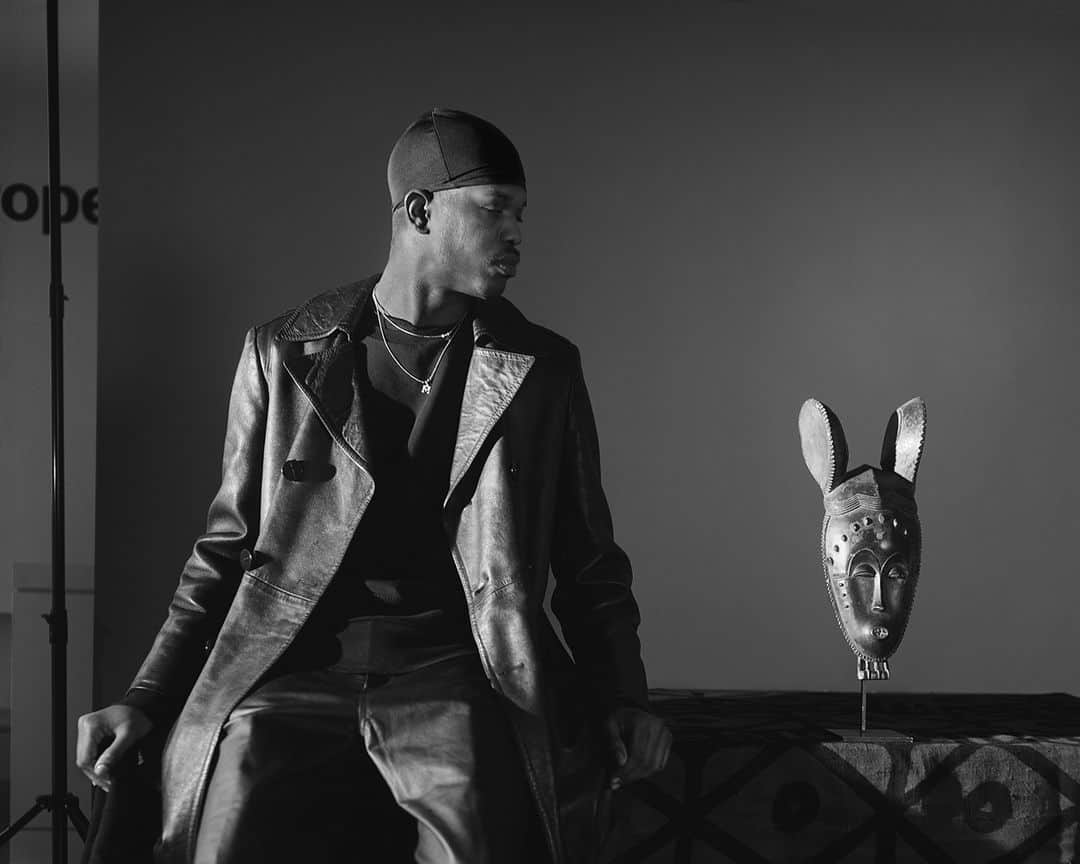 のインスタグラム：「In John Edmond’s Untitled (Marion & Yaure Mask), a stylish young man, wearing a skull cap and leather garments, contemplates a wooden mask by a Yaure tribe artist from Côte d’Ivoire that was once owned by the late Black American writer Ralph Ellison. As part of his solo exhibition A Sidelong Glance, the Museum invited the Brooklyn-based artist to create new work featuring objects from Ellison’s collection. Edmonds made this picture in the Museum’s Beaux-Arts Court, where the European Art collection is currently installed, evident by the letters “rope” (clipped from “European”) visible behind the studio backdrop. While many of Edmonds’s previous photographs feature models touching or in close proximity to objects, the physical distance between the two in this picture highlights the various barriers created by art history and its institutions. It also serves as a metaphor for the African diaspora and its relationship to Africa.⁠ ⁠ This #BlackHistoryMonth, we’re examining how John Edmonds centers African art in his photography as a site of identity, power, and artistic ingenuity.⁠ ⁠ John Edmonds (American, born 1989). Untitled (Marion & Yaure Mask), 2020. Digital silver gelatin photograph. Courtesy of the artist. © John Edmonds」
