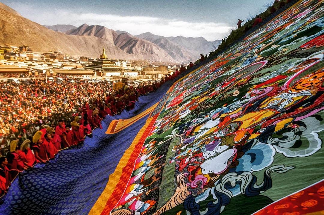 Michael Yamashitaのインスタグラム：「It’s the second week of Monlam, the Great Prayer Festival. In past years, the annual "sunning of the Buddha" is one of the most important ceremonies at Labrang Monastery which is regarded as the top Tibetan Buddhism educational institution in China.  In this ritual, the world's largest Thangka of Buddha (90ft in length, 40ft in width) is unveiled at first light on the side of a mountain to the delight of thousands of monks, pilgrims and worshipers. By just witnessing it, the audience is said to gain merit on the road to enlightenment. However it’s doubtful  if Buddha will get to see the sun due to covid restrictions this year. #monlam  #labrangmonastery #xiahe #gansu #sunningofthebuddha #tibetanbuddhism #thangka」