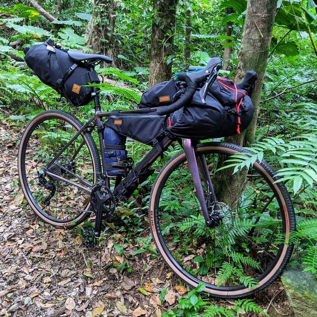 山下晃和さんのインスタグラム写真 - (山下晃和Instagram)「【BIKE&CAMP】ジャングル、やんばる。  キャンプ道具積載のポイントはマスの集中化 身体に近いところに重たくて嵩張らないものを入れる（特に水分、電池、工具類）　　  衣類、寝袋などをスタッフサックに入れずに押し込んで形を整える 左右均等に  フロントにサスがない自転車の場合は、前後タイヤの空気圧を変える。自分はフロントを10PSI抜く（リアの数値より引き算）。それがサスペンション効果となると同時に、前上がりが少なくなるので、前進するスピードが変わってくる  他にも自転車キャンプツーリングは学びが多いので、WEB連載のほうやカタログのほうでくわしく書く予定✎  #自転車旅の学校 #色をたくさん使わないとオシャレになりますこれはファッションも一緒だね #モトは前後タイヤの空気圧違います #bikeandcamp #自転車キャンプツーリング #自転車キャンプ #bikecamping #バイクパッキング #バイクパッキングは物理学的な要素あります #touring #bikepacking #輪行 #旅 #travel #CAMP #キャンプ #沖縄 #Okinawa #グラベルロード #GRAVEL #自転車 #bicycle #旅自転車 #自転車旅 #旅サイクリスト @cannondalejapan @ridecannondale  #ridetopstone #topstone @restrap」2月24日 22時26分 - travel_akikazoo