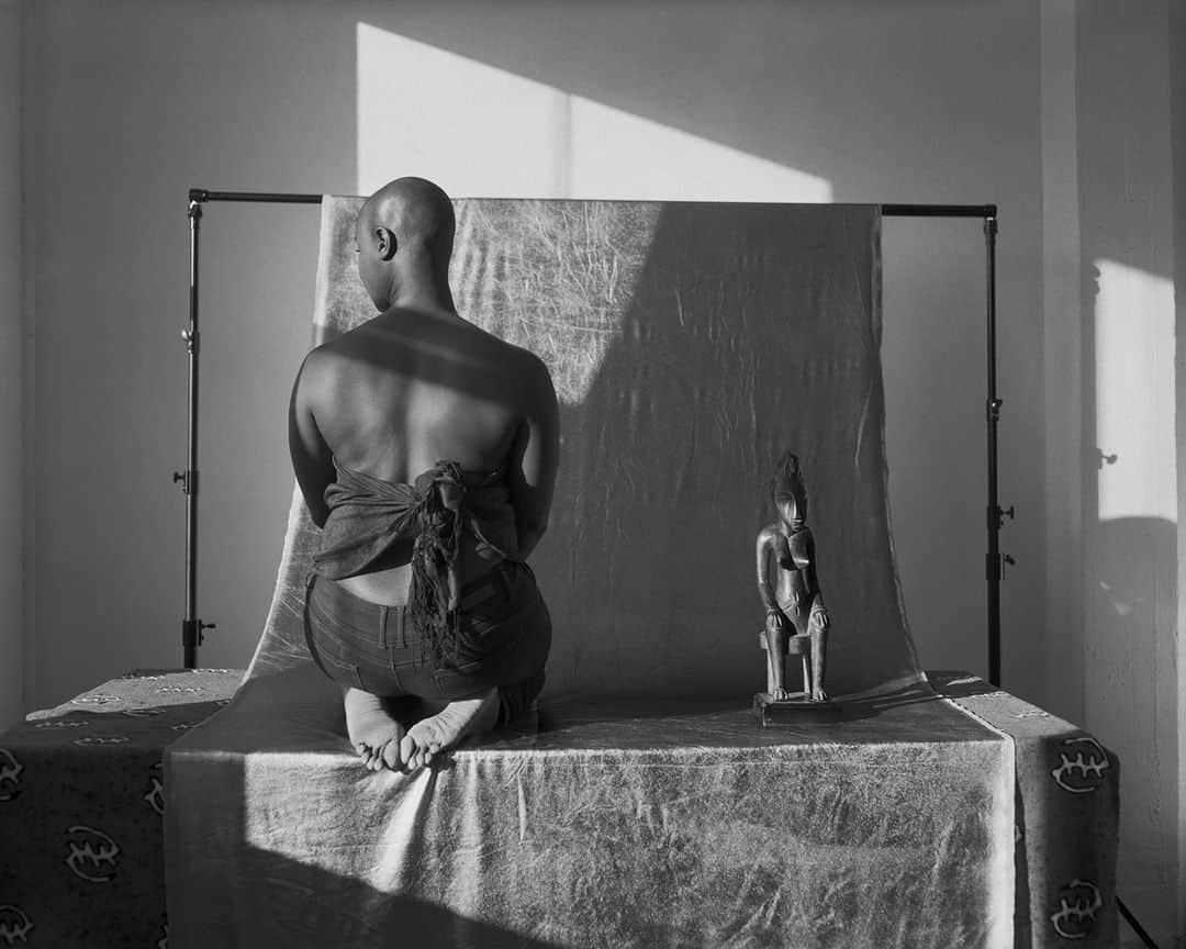 のインスタグラム：「In John Edmonds’s large black-and-white photograph, sunlight washes over the artist Ja’Tovia Gary, whose seated pose echoes the carved female figure by a Senufo artist next to her. “Staying true to my own beliefs, I often make pictures in my studio in observation of the passage of time,” says Edmonds. “Intimacy and picture-making as labor and an act of love is a recurring theme throughout much of my practice.” The natural light from the window and the studio backdrop also call attention to the medium of photography itself and the process of picture-making as an important act of agency. Often photographing friends or acquaintances, Edmonds frequently obscures his collaborators by having them turn away from the camera or using photographic techniques like double exposure and solarization.⁠ ⁠ This #BlackHistoryMonth, we’re examining how @johncedmonds centers African art in his photography as a site of identity, power, and artistic ingenuity.⁠ ⁠ John Edmonds (American, born 1989) Untitled (Light Passing over Ja’Tovia and Senufo), 2019. Digital gelatin silver photograph. Courtesy of the Artist #bhm」
