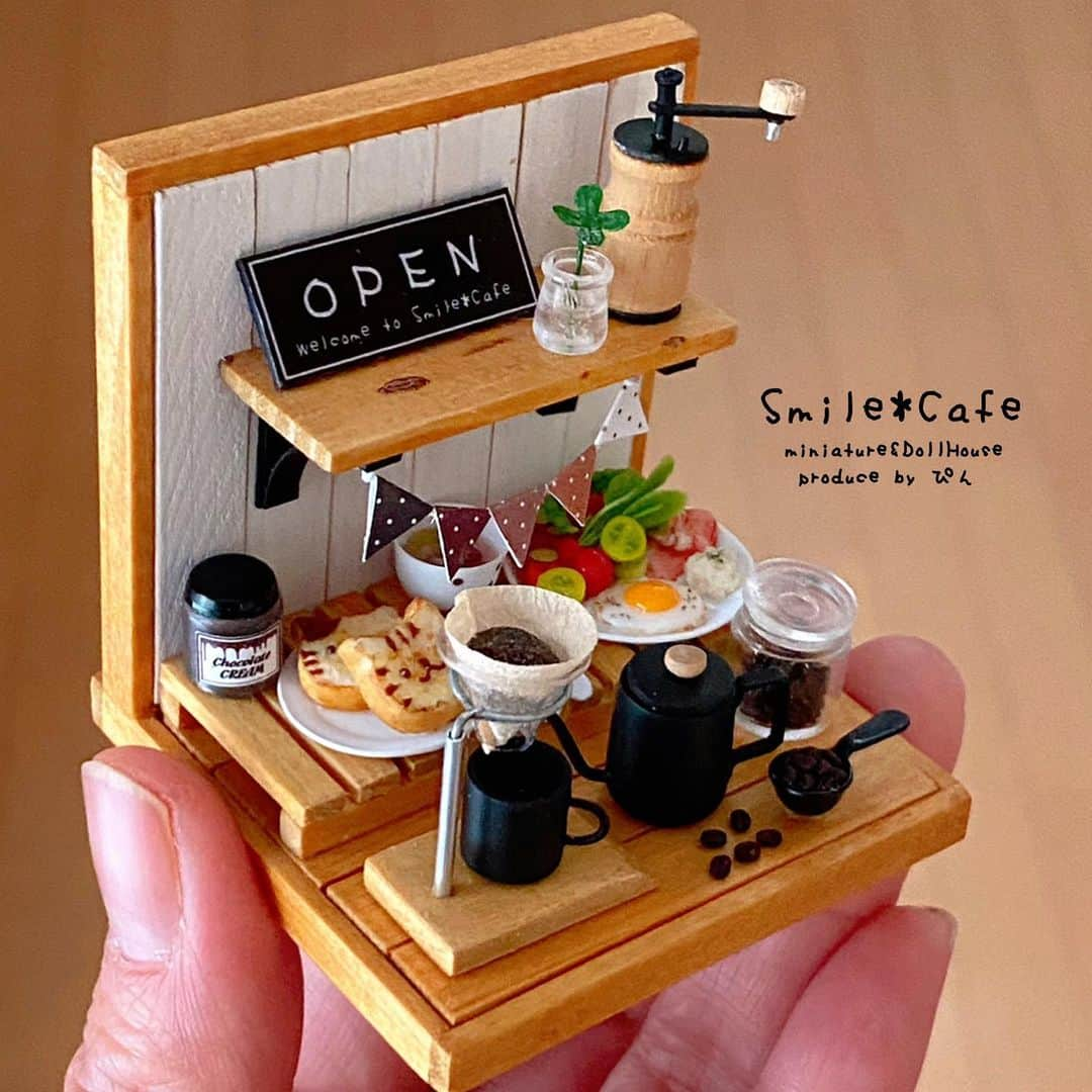 すまいる*工房(ぴん) のインスタグラム：「* コーヒーのある朝食セット☕ アップ写真撮りました𓈒 𓂂𓏸 * ポットの形が 定番なポットと今時なポットの2種類あり 今時なポットの方は 目玉焼きかスクランブルエッグバージョンの2種類あり それぞれ、ホワイトとブラックの色違いで 作りましたので全部すこ〜しずつ 違うことになっています😊 * 定番ポットの方はガーランドがカラフルな色合いで🌈 今時ポットの方は、コーヒーカラーのガーランドになっています☕ * お好みのセットを見つけて頂けたら嬉しいです(ᵒ̴̶̷ ᵕ ᵒ̴̶̷⁎) * 販売方法は、Instagramでの抽選にするか 私個人のFc2のショップカート🛒を持っているので そちらを使い販売するか迷っています。 * 販売するなら 先着順よりも 抽選販売が良いのですが 最近のインスタでは 偽アカウントを作られたりと 色々あるようなので 偽アカウントから 変なDMが届いてご迷惑掛かるかも…と そんなことを考えると カートを使った方が良いのか悩んでいます🤔 * カートですが、数年触っていないので ちゃんと使えるか少し不安もあるのですが 今晩設定してみて使えそうなら ショップでの販売にしようかなぁと 考え中なので販売方法確定しましたら ストーリーでお知らせしますので もう暫くお待ちください🙇🏻‍♀️ * 販売は明日か明後日の夜に予定しています🙆🏻‍♀️ * #ミニチュア#ドールハウス#miniature#DollHouse#カフェ#すまいる工房#コーヒーのある暮らし #カフェ #コーヒー #コーヒーミル#コーヒーすきな人と繋がりたい #coffee#Cafe#コーヒーミル #朝食#朝食セット#モーニングプレート #ミニチュアフード#miniaturefood」