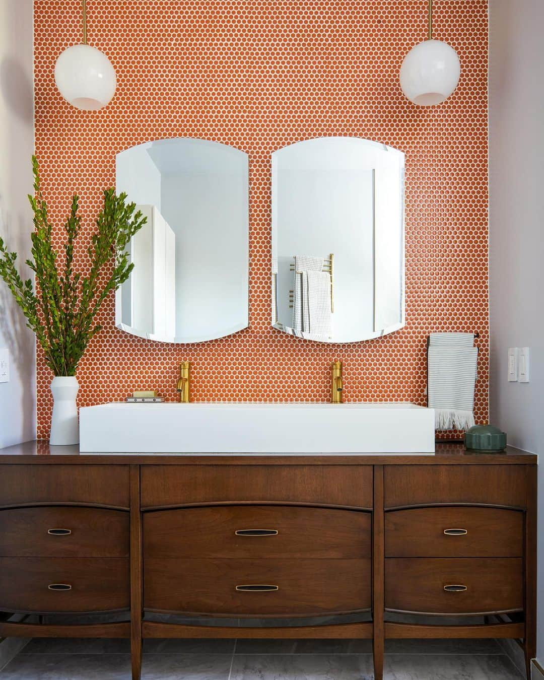 Sweeten Homeのインスタグラム：「A dresser-turned-vanity becomes the centerpiece in this LA bath remodel when renovators Liz and Kevin came across a vintage-modern walnut dresser they liked. Working with a woman GC from Sweeten, the dresser was converted into a vanity with double sinks and storage! And that orange pennytile backsplash? Gorgeous 🤩⁠⁠ ⁠⁠ Backsplash: Floor & Decor⁠⁠ Faucet: Kingston Brass」