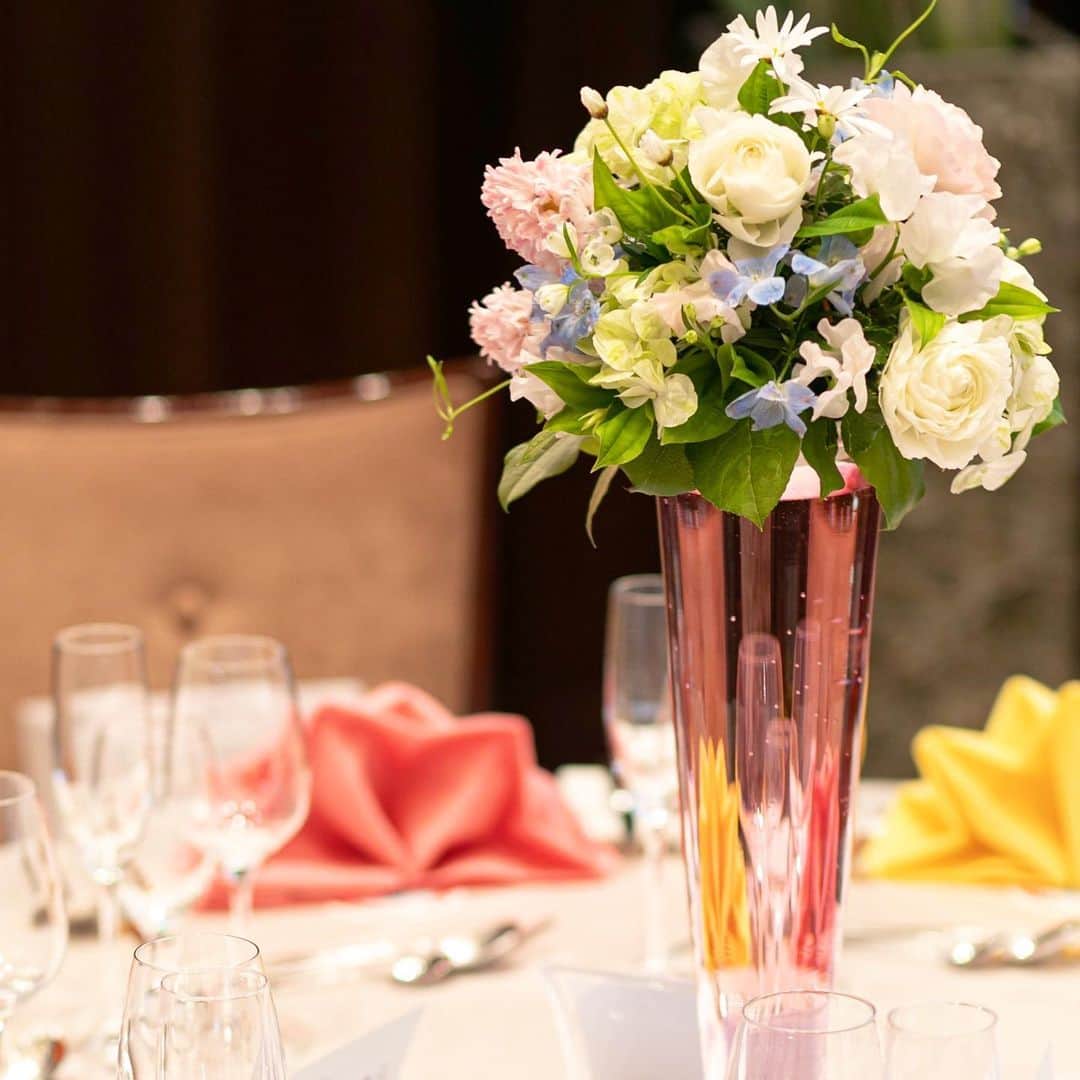 東京タワーの麓の結婚式のインスタグラム：「🗼 テーブル上を華やかにしてくれる装花💐  テーブルクロスだけでなく ピンク色の水を取り入れた装花🌷とカラーナフキンが 会場内をより一層明るい雰囲気に🌈✨  ナフキンはお好みの1色でも素敵ですが テーマに合わせたカラーを取り入れると統一感が出て おふたりだけのオリジナル空間が広がります🤗💕  気になる方ははプランナーまで気軽にご相談くださいませ♪  詳細は(@theplaceoftokyo )まで♡  #theplaceoftokyo #プレイスオブトウキョウ #プレイスオブトーキョー #プレイスオブ東京 #ザプレイスオブトーキョー #ザプレイスオブ東京 #ザプレイスオブトーキョー #ゲストハウス婚 #令和2年婚 #東京タワー #東京タワーが好き #tokyotower #tokyowedding #東京タワーが見える #2021婚 #2021wedding #2021夏婚 #2021秋婚 #2021冬婚 #結婚式準備 #結婚式  #ちーむ2021 #東京花嫁 #プレ花嫁準備 #ぷれ花嫁 #プレ花嫁 #会場装花 #カラーナフキン #オリジナリティ」
