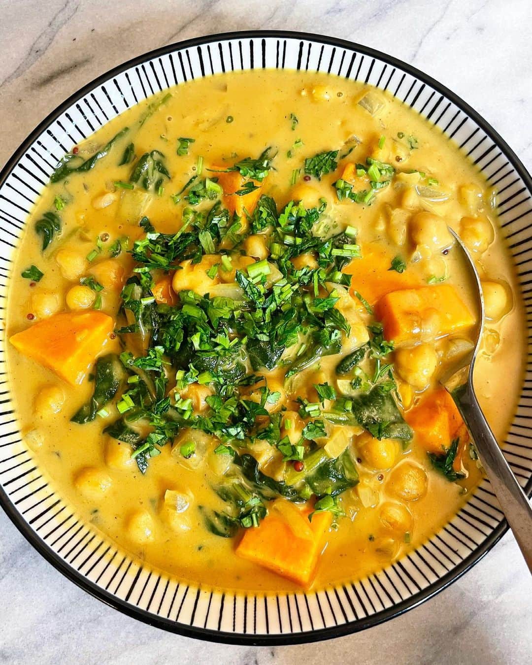 金原杏奈のインスタグラム：「Easy 20min chickpea & sweet potato curry 😎  #Repost @kitchenpharmacy  with @get_repost ・・・ 寒かった日や忙しかった夜は ヴァータが上がり気味。 そんな日は温かいほっこりする 食べ物が食べたくなる😌 ・ そんな日常に加えて女性の黄体期は ヴァータを癒す食事が向いています。 この時期は新陳代謝が上がるので 食欲が増すのは自然の原理。 ・ 穀物、野菜、炭水化物など秋の食品を 意識してみると良いみたい🙆🏻‍♀️ 良質なオイルも忘れずに！ しっかり食べる事が大切です！ ・ スープとしても食べられるカレーは 時間が無い夜でもパパッと簡単に作れて カラダも満足するのでリピート率高め！ 入れる具材やスパイスを変えるだけで 印象も変わるから飽きないです😊 ・ 今日のレシピ（２人分）  アボカドオイル（お好みのオイル）大さじ１ ニンニク　少々 玉ねぎ　1/2個 *マスタードシード　小さじ1/8 *クミン　小さじ1/8 *ターメリック　小さじ1/8 カレー粉（またはルー）お好みの量 ひよこ豆　１缶 さつまいも　小１個 ほうれん草　半束 ココナッツミルク　１缶 お水　1/2カップ パセリ　トッピング用  *のスパイスは入れなくても◎  野菜を細かく切ったら、鍋に油をひいてニンニク、玉ねぎ、*のスパイスを入れ香りが出るまで炒める。そこにひよこ豆とさつまいもを加えさらに炒めたら、ココナッツミルクとお水を投入する。沸騰寸前でカレー粉とほうれん草を加えて煮込んだら完成！ ・ #あーゆるライフ」