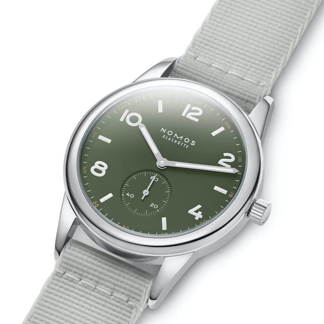 のインスタグラム：「Club automatic olive is a reliable companion for wherever life takes you, whether that’s the great outdoors, the streets of downtown, or 200 meters underwater. Its waterproof light gray textile strap complements the green dial and brings the right amount of casual to any look.  #nomos #glashütte #c#clubautomatic」