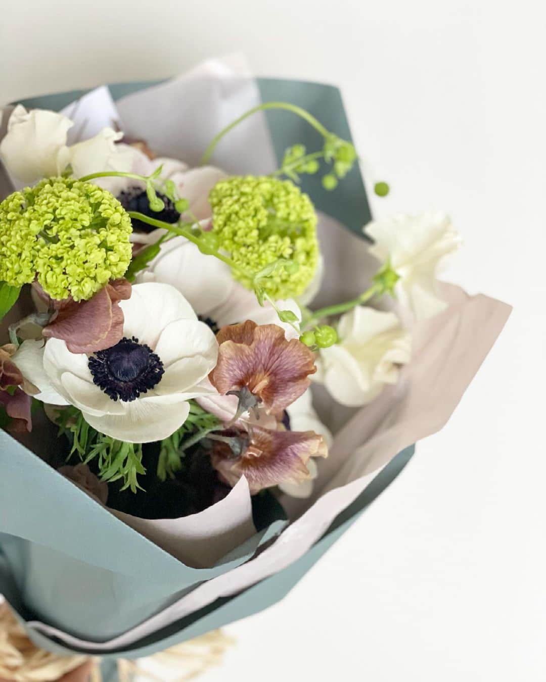 猫沢エミさんのインスタグラム写真 - (猫沢エミInstagram)「3月21日（日）雨。  ナイスカップル 整体師のミノルくん @flexibody.jp と、私の英語の先生ホアン @borderlessjp から、素敵な花束が届いた。 プチタプチ @petit_arai さんのアレンジメント、さすがのお洒落さ。すごく好み。  レッスンが終わってさっそくイオちゃんの祭壇に飾らせていただいた。  なんて可愛いんだろう💕  この気持ちって、小学生の娘のいるお母さんが、お嬢さんの勉強机まわりを可愛くアレンジして嬉しいみたいな気持ちなのかな？なんて思った。  病気になると、いろんなものが汚れたり殺伐とするのがリアルではある。現実は、お洒落なんて言葉とは真反対の介護現場なんだけど、今回の見送りを通して、私はイオちゃんを出来うる限り、清潔でお洒落な環境に置くことを大切にした。  それはおのずと気持ちの良い空間や雰囲気を生み出して、結果、イオの進行する病状の過酷さを具体的に和らげたと感じている。  正しい意味でのお洒落って、どんなときも大事なんだなぁと思った。死の間際ですらも。お洒落なままイオは天国へ旅立ち、残されたお骨もお洒落なお花に囲まれている。  こうゆうのって、すごくいいなと思う。  #猫沢イオ #イオの扁平上皮ガン日記  #ミノルくんホアンあらいさんありがとう💐 #死とお洒落を哲学す　#哀しい雰囲気を排除する大切さ」3月21日 16時05分 - necozawaemi
