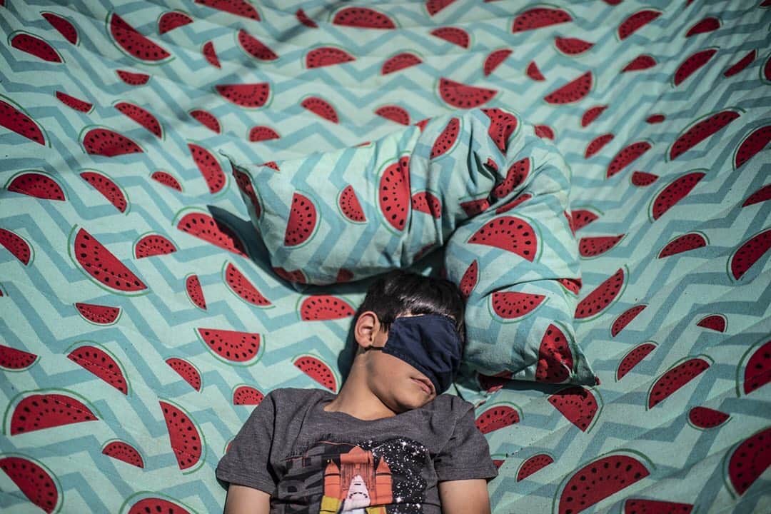 National Geographic Creativeのインスタグラム：「Photo by @annaboyiazis / How do you say watermelon in Arabic? Jordanian-American Mohammad, 8, rests on a hammock in California, shielding his eyes from the afternoon sun. Mohammad’s mom Huda AG is instrumental in helping Iraqi and Syrian families acclimate. I made this picture as I highlight how the new arrival community of Syrian refugees and asylum-seekers in California is contributing to America during the pandemic.  This work is supported by the @insidenatgeo COVID-19 Emergency Fund for Journalists. In collaboration with @miryslist and the @newarrivalsupperclub  To see additional stories focused on human rights, public health, and women and girls’ issues, follow me @annaboyiazis  #california #dream #watermelon」