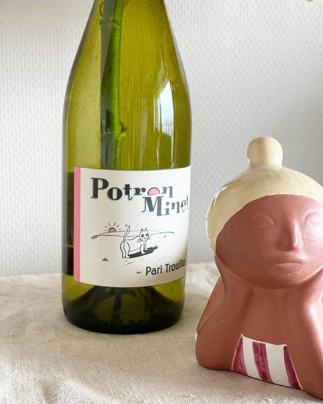 猫沢エミさんのインスタグラム写真 - (猫沢エミInstagram)「薔薇の一輪挿しにしているこのワインボトルには、かわいい猫のエチケットがついていて、ちょっとした思い出がある。  イオの闘病期の中盤ごろだったかな…元彼がイオをみていてくれるというので、病になってから初めて近所のワインバー @kotori_wine さんへ、友達と息抜きに出かけた。  息抜きしようとしても、話すことはイオのことばっかりだったけど、猫楽園（と、私は当時自宅を呼んでいた。猫のホスピスという意味で）からほんの少し離れることが必要だったと思う。  ことりのご主人は、決してイオのことには直接触れてこないのだけど、さりげなく猫エチケットのワインを選んでくださったのが、とても嬉しかった。  それで持ち帰ってきた。そして今も大切に持っている。  お酒ってさ、ただ本人が呑んで酔うだけのものでもなくて、必死に誰かを支えるために呑む酒もあるわけで。そうしたドラマを取り上げられている今、やりきれない人がどれほど多くいるだろうと思いを馳せる。  呑んだ人が、呑めたから救えたり、支えられた命とかあるんだと思うから。  イオちゃんのボトルに、今日も勢いよく水を吸い上げる薔薇が咲いている。  #イオちゃんフォーエバー　#東京下町時間 #猫沢銘店　#呑まなきゃやってられないときってみんなある」5月8日 13時21分 - necozawaemi