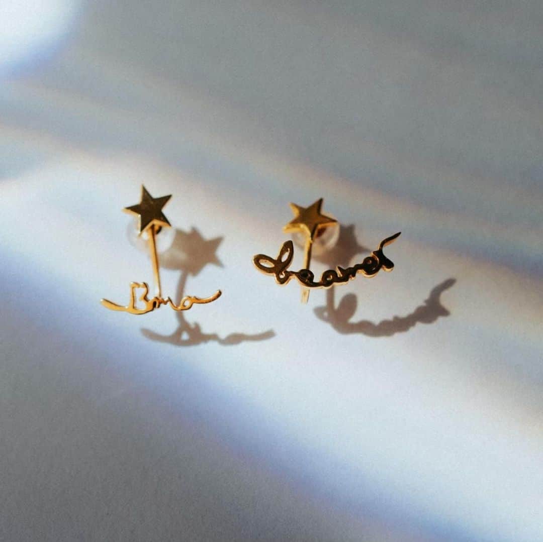 MiracleVellMagicのインスタグラム：「私がデザインしたピアス&イヤリング🥴❤︎ 気に入ってくれたかしら？✨  ベル手描きの “I’m a dreamer”の文字がね、それはそれはもう忠実に形取られていて…！ こんなに可愛いピアスが出来上がるなんて。製作スタッフのみなさん、工場で働く方々に感謝です。😭  素材はK10(10金)。 金属アレルギーの人でもつけられて、なおかつ “一生もの” として大事にできる丈夫さを重視してこの素材にしました。😌  夢を追いかけている人、何かに挑戦している人のお守りになるように想いを込めて作ったんだ。  夢を追いかけることってさ、ワクワクドキドキをくれるのと同時に、真っ暗な洞窟を手探りで進んでいくような、怖さを伴うものでもあるんだよね。  不安な気持ちになった時、諦めてしまいそうになった時、ふと鏡に映ったピアスを見て”そうだ、私はdreamer(夢追い人)。やっぱり私、夢を追いかけていたいんだ。” そんな気持ちになってもらえたらいいなぁと思ってます☺️  夢を追うことは、人生を豊かにしてくれる。その夢の規模は関係ないよ。どんなに小さな夢でもあなたの心がときめいていればそれは立派な夢！そして途方もない大きな夢も、それが叶ったって叶わなくたって、追いかける時間にものすごい価値がある✨  私も人生でやりたいことがいっぱいあるんだ！！楽しみでたまらないよ。😚 共に夢を追いかけていこうね！✨✨  “I’m a dreamer” ピアス＆イヤリングは、プロフィールのリンクからチェックしてね！☺️✔︎」