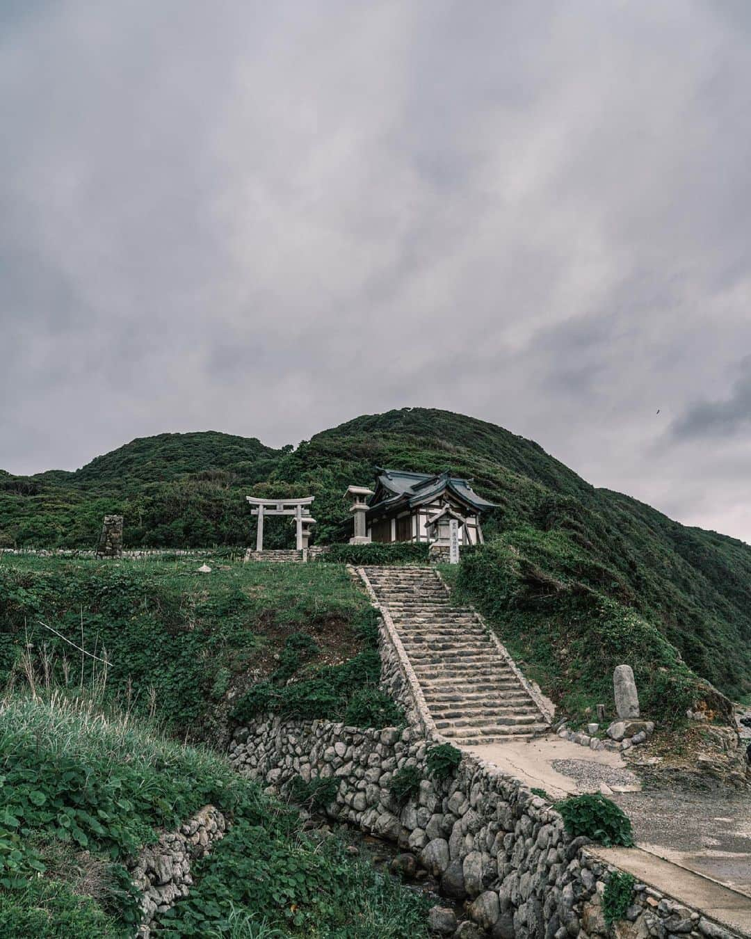 SHOCK EYEさんのインスタグラム写真 - (SHOCK EYEInstagram)「入島禁止の世界遺産、神宿る島、 沖ノ島を拝む為に、フェリーに揺られ大島に渡る。  なぜなら大島には沖ノ島を遥拝する沖津宮遥拝所があるから。  連れ添ったスタッフが皆「おー！」と声をあげてしまうほどの景観に立つ社殿。 目の前に広がる海、、 目を凝らすとその奥にうっすらと島が見えた✨  空から鳶が僕らを出迎えてくれる。  物音ひとつしない神域に聞こえるのは風の音と波の音だけ。  そこはまさに非日常だったよ。  沖ノ島に向け手を合わせ、ここに来れたことへの感謝を伝える。  はあ、、、 心がスッと整う感覚。。  しっかりとパワーを頂いたよ。 すごい場所だった。  #宗像大社 #沖津宮 #沖津宮遥拝所  #世界遺産 #沖ノ島 #神社 #shrine #munakatashrine #worldheritage」6月25日 9時19分 - shockeye_official