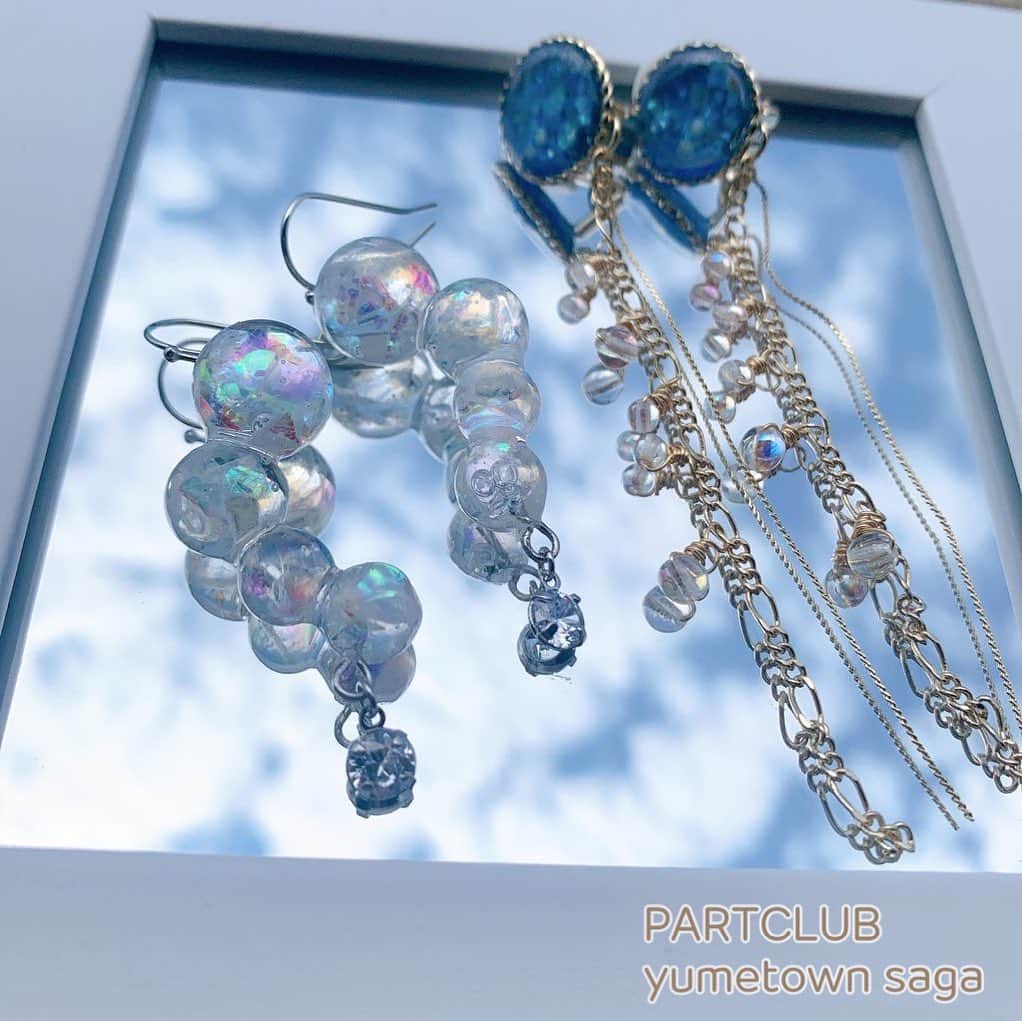 パーツクラブ Partsclub スタッフオリジナル商品のインスタグラム：「🌼ゆめタウン佐賀店　スタッフ作品です🌼     ☁1枚目☁ 左側のピアスは、ドーム型のモールドにオーロラホロを沢山詰め込んでシャボン玉ピアスを作りました！ 右側のイヤリングは、ブルーのレジンにシェルとラメを入れて、チェーンにオーロラのチェコビーズを付けました。 オーロラは、室内ではもちろん外に出ると更にきらきら輝いてとてもきれいです✨ 是非、オーロラパーツでアクセサリーを作ってみてください❣     ☁2枚目☁ 今回は梅雨をテーマに、紫陽花のイヤリングをつくりました！ レジンを使い透明感を出しつつ、和菓子の様な見た目にもこだわりました♡ 左側のピアスは、最近人気の連結パールピアスです。 繋げるだけで簡単にできるので是非作ってみて下さい✨     ☁3枚目☁  レジンで梅雨の雨粒をイメージして作りました！！表面がぷくぷくしていてとても可愛いです。 キュービックジルコニアもキラキラ輝いてます✨✨ 涼しげで今の季節ぴったりです！  ※こちらはスタッフ作品のためレシピはございません。 ※商品の取扱は店舗によって異なります。ご了承ください。  ただいま、お得なSALE開催中です！  🌷スワロフスキークリスタルが20%OFF💎 🌷対象の完成品アクセサリーが30%OFF➕2Buy20%OFF❗️(1部対象外あり) 🌷対象のマスク･マスクアクセサリーなどマスク関連商品が50%OFF❗️(1部対象外あり)  ☁️店内教室開催中です☁️ 現在、レジンのお教室を開催しております。 日程🗓 7/1・7/8・7/22・7/29 時間🕐 13:00〜(1時間30分程予定)  店頭･お電話でもご予約受け付けております。 佐賀店☎️ (0952)32-0582  大人気の新商品も続々再入荷しています❗️ぜひご来店下さい❗️   #シャボン玉ピアス   #オーロラアクセサリー   #キラキラアクセサリー  #紫陽花イヤリング  #女優ピアス  #水面レジン  #レジンアクセサリー  #ゆめタウン佐賀店  #partsclub   #パーツクラブ  #partsclubstaff   #パーツクラブスタッフ  #パーツクラブ公式アカウント  #佐賀」