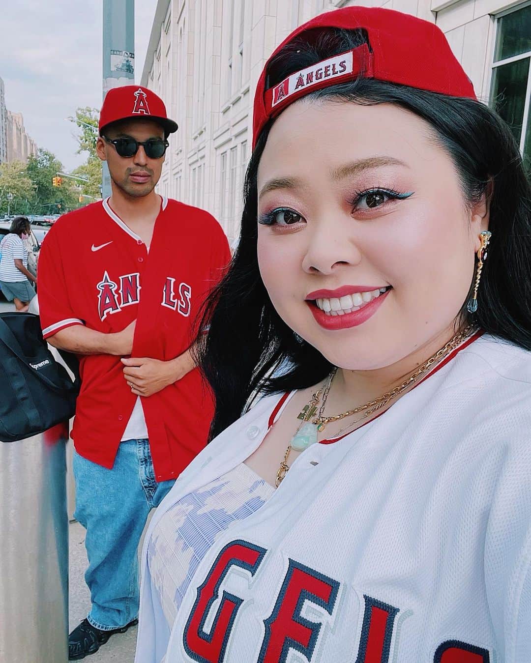 渡辺直美のインスタグラム：「本日は大谷選手を拝みに行きました🙏  編集頑張ったご褒美に 1番前の席を奮発して購入しました😆 あまりの迫力に 興奮してアイスティーを盛大にこぼし、 洋服半分茶色くなったけどそんなんどうでもイイくらい貴重な経験でした🙏🤣  ヤンキースタジアムで大量のヤンキースファンの中赤いユニフォームで乗り込んだのは最初怖かったけども、 ヤンキースファンが私達を見るなり 「おめーが大谷ファンなのは仕方がねぇ、我々も今日は大谷を見に来たんだw」と沢山の方に言われました🤣🙏 敵のファン達も虜に❤️‍🔥流石でございます🙏大谷選手が登場するたび大歓声の嵐✨  隣に座ってたお父様方も、大谷選手はもちろん、ヤンキースの歴代の日本人選手達の事を興奮しながら私たちに熱弁してました😆✨すごい仲良くなったよ🤣  あまりにも近い席だったので変に緊張しちゃってさ(自分で選んでおきながらw) 邪魔にならないように、小さな声で応援しましたw 逆に自意識過剰w これからも応援します🙏  何事も影響されやすい私ですから… 野球やりたい願望がでてきてもうたw ニューヨークでバッティングセンターあるか調べてきます🥰✨  スポーツ最高😭 これからもいろんなスポーツ見に行きたい😆❤️‍🔥」