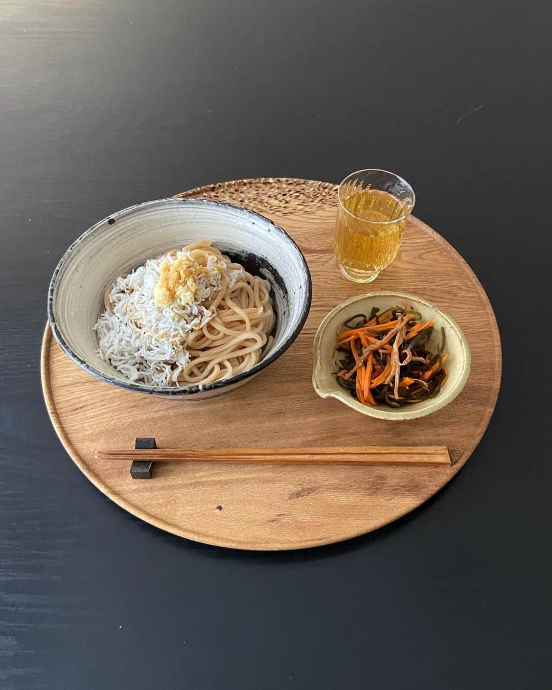 のインスタグラム：「ひとりのお昼ごはんは手早くできて、好きなものを。今日は少し暑かったので冷やしうどん。最近ハマっている全粒粉のさぬきうどん(乾麺)。粉の香りと旨味があるのでシンプルに。おろししょうがと釜揚げしらす、胡麻油と生醤油。刷毛目の大きめ茶碗がちょうど良い。昨日、漬けた松前漬けを副菜にして味見。松前漬けといっても数の子なし！☺️スルメと昆布とニンジンだけ。松前漬けとは言わないですね…。昆布の粘りがとろんとろんで最高です。おっと、私も野菜が足りていませんね😅　さぁ、午後もがんばりましょう！と思ったらそろそろお迎えの時間。どうしてこんなに一日はあっという間なのでしょう…。」