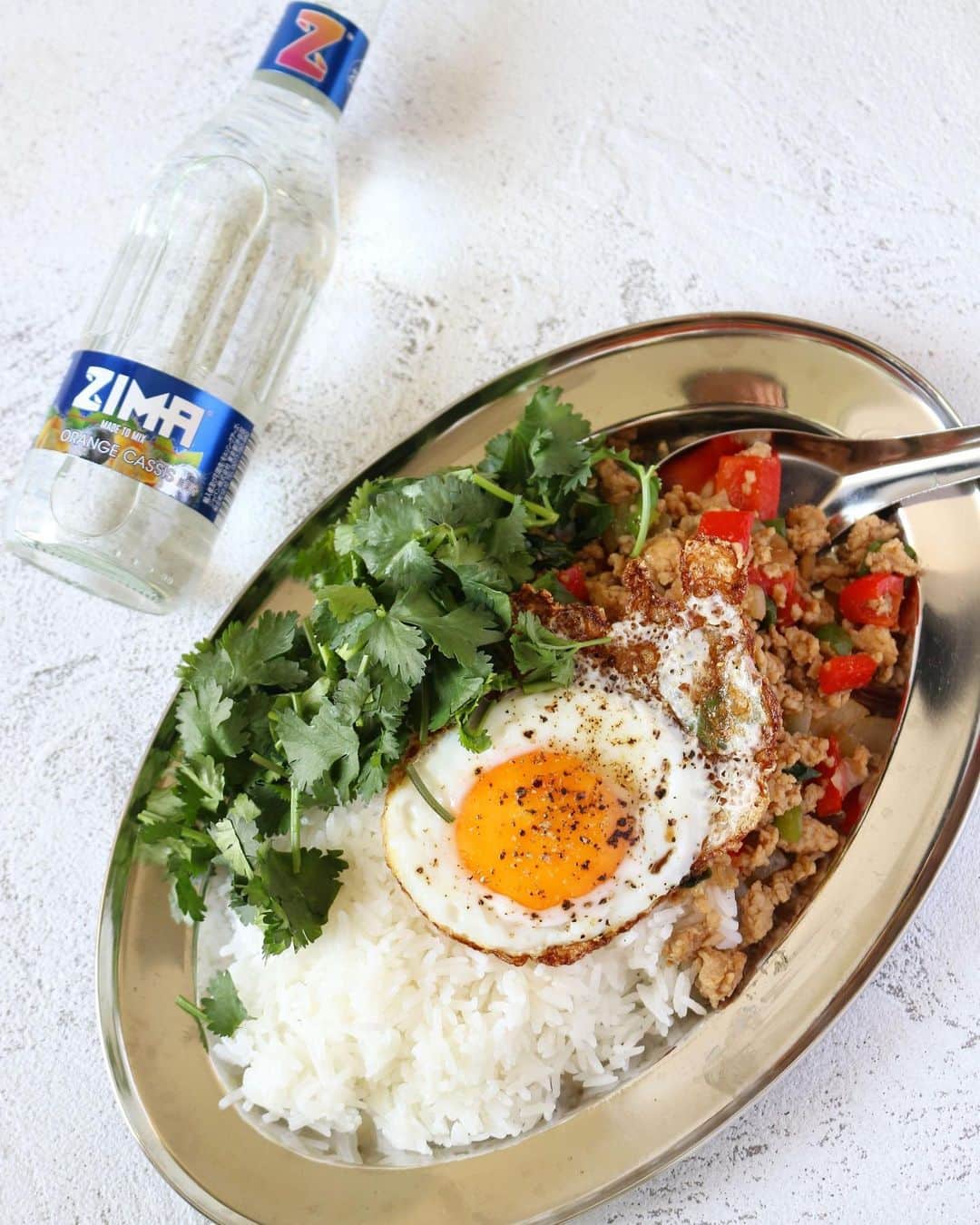 ZIMAのインスタグラム：「🍽新ZIMAと相性ピッタリ！Zimatchレシピ紹介🍽 ⁡  本日のレシピは【ガパオライス】😋 夏の終わりに甘辛ガパオライスと一緒にZIMAの新フレーバーを🎶 スパイシーな風味の中にある、爽やかなバジルの香りに合わせるなら、やっぱりフルーティで優しい味わいのオレンジ＆カシス❗ ついついクセになるエスニック料理はお酒もすすみます✨ ⁡ ＝＝＝＝＝＝＝＝＝＝＝  【ガパオライス】レシピ  ＝＝＝＝＝＝＝＝＝＝＝ ⁡ 【材料】2人前 ・鶏ひき肉　200g ・玉ねぎ　1/4個 ・パプリカ（赤）1/4個 ・ピーマン　1個   ・鷹の爪　2本 ・にんにく　１かけ   ・バジル(生)　10枚 ・ごま油　大さじ１ ⁡ A ・酒　大さじ１ ・ナンプラー　大さじ１1/2 ・オイスターソース　大さじ1/2 ・ウスターソース　大さじ１ ⁡ ・玉子　2個 ・サラダ油　大さじ２ ・塩・ブラックペッパー　適量 ・ごはん　400g   ・パクチー　好きなだけ ⁡ ⁡ 【作り方】 ①にんにくは細かくみじん切り、玉ねぎ・パプリカ・ピーマンは5㎜角のみじん切り、鷹の爪は２㎜幅の輪切りにする。 ⁡ ②フライパンにごま油を熱し、にんにく・玉ねぎ・鷹の爪を炒め、たまねぎが透き通ったら鶏ひき肉とパプリカ・ピーマンを加え炒める。 ⁡ ③肉に火が通ったらAを加えて絡めるように炒め、調味料がよく絡んだらバジルをちぎりながら加えさっと混ぜて火を消す。 ⁡ ④別のフライパンにサラダ油を強火で熱し、玉子を割り入れ揚げ焼きにしたら塩・ブラックペッパーをかける。 ⁡ ⑤器にごはんを盛り、③・④・パクチーを盛り付ける。 ⁡ ＝＝＝＝＝＝＝＝  他のレシピも見てみたい！という方はZimatchサイトへGO‼💨  新しくなったZIMAとおうち料理の最高の出会いが見つかります✨  くわしくは公式サイトをCHECK👀 ⁡  #ZIMA #ジーマ #Zimatch #ジーマッチ #新ZIMA #新しい #リニューアル #酒 #お酒 #お酒好き #簡単レシピ #レシピ #クッキングラム #クッキング #instafood #foodporn #お酒好きな人と繋がりたい #フードペアリング #料理 #ガパオライス #タイ料理 #スパイシー  #家飲み #宅飲み #ベランピング #家キャンプ #おうちレストラン #おうちごはん #おうち時間 #おうち居酒屋」