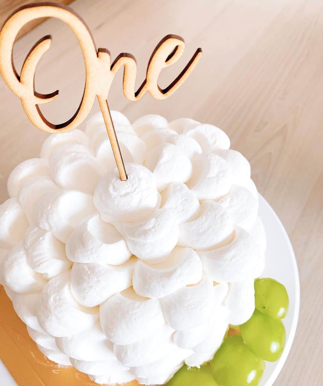 橋本まゆのインスタグラム：「スマッシュケーキ🧁 スタジオで使う予定だったのを自宅に送って頂いた @smashcake.jp のケーキにマスカットをトッピング🍇 ⁡ 義理家族にも見守られながらのいざ実食💪🏻 ⁡ 結果は…娘らしく終わりました🌿 普段手掴みやフォークで食べたりするからスマッシュしながら食べれるでしょ〜って思っていたけれど慎重な娘はフリーズ（笑）食べさしてあげると食べた！でも手に付くのは嫌だったらしく最後は食べる事すら拒否🙌🏻 スマッシュせずに終了しました〜🤣 ⁡ これも良き思い出💗 残りは大人が美味しく頂きました❤️  #1歳誕生日#スマッシュケーキ #happy1stbirthday#birthday #1歳誕生日#女の子ベビー#女の子のママ」