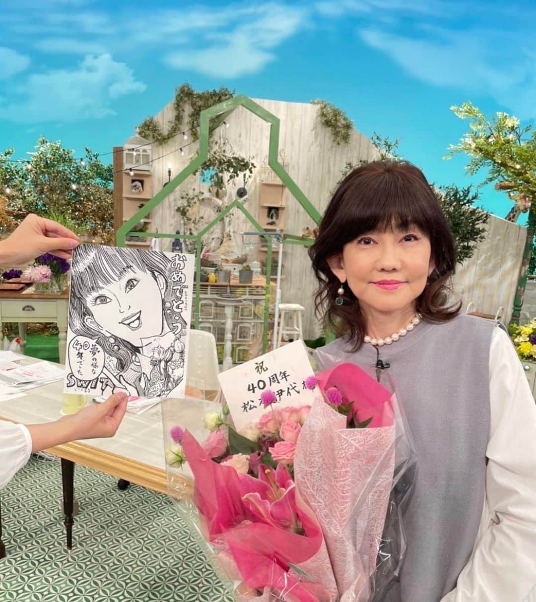 のインスタグラム：「東海テレビスイッチ  40周年！ ということで 番組中 サプライズで お花いただきました🌼🌸 同じ数のバラだそうです🌹  感動〜😭❤️  ありがとうございました😭  #東海テレビスイッチ #スタジオのセットには動物がたくさん #帰りの名古屋の駅ではいつも応援してくださる方々からお花いただきました #そしてお弁当と可愛い ケーキも #美味しかった #ありがとう #いつも番組に送ってくださる似顔絵 #持ってくれているのは速水アナ お衣装 #saaageboutique #松本伊代 #iyomatsumoto」