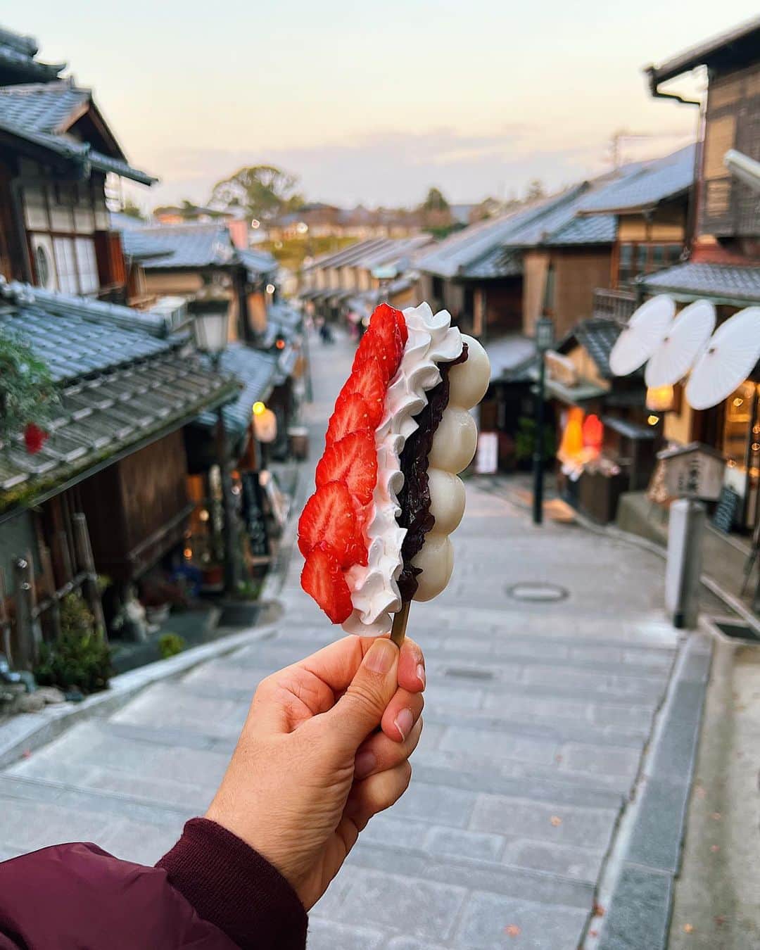 Girleatworldのインスタグラム：「Ichigo Daifuku Dango at Ninenzaka in Kyoto, a marriage of two beloved Japanese dessert: Ichigo Daifuku (strawberry mochi with red bean paste) 🍓and dango (sweet rice dumplings) 🍡 And yeah, I was holding on to the dango very tightly bc I was so scared of dropping it before I get to take a bite 🤪  Four years ago, I took a picture of the more traditional Ichigo Daifuku, right around the corner from this spot. I had been to Kyoto twice, once at its prime during sakura season and once during momiji leaf season. This time, I arrived to a very different Kyoto - very quiet with almost no foreign visitors, and so very bare. There were only a handful other people on this street even though it was only 3pm. I suppose I was grateful to experience Kyoto this way, but I couldn't help feeling sad too. It felt like a crime enjoying such beautiful place almost to ourselves.  #shotoniphone #iphone13promax #ichigodaifuku #dango #kyoto #ninenzaka #ichigo #🍡 #🍓」