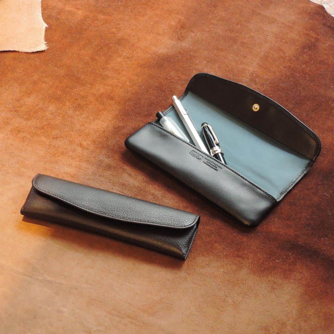 革財布のお店mic 自由が丘店のインスタグラム：「限定生産品のペンケース🖊 在庫が残り少なくなってきました😳  オランダ産原皮のキップレザーを使用しています。 心奪われるような、柔らかく滑らかな質感が特徴です。  写真2枚目をご覧いただくとわかりやすいのですが、革を裁断する場所によってシボやシワの入り方が異なるのも特徴です☺️ (ちなみに上がブラック、下がダークブラウンです。めちゃくちゃ色味が似ています。笑)  ペンは太さにもよりますが3〜4本ほど収納できます。 持ち運びやすいサイズ感で、軽いので負担にもなり辛いですよ\❤︎/  カラーによって裏地の色味が異なります。 革がブラック→裏地はブルー 革がダークブラウン→裏地はオレンジ  名入れ刻印も入れられますのでギフトにもおすすめです🥰  自由が丘店では現在2色とも在庫がありますので、ぜひお越しくださいませ🎵  刻印の入る場所や、裏地との組み合わせなど、オンラインストアでさらに詳しくご覧いただけますのでチェックしてみて下さいね✔️   ~~~~~~~  ヴェルニカシリーズ ペンケース 税込み4,950円  2colors ブラック／ダークブラウン  ~~~~~~~   #mic  #革小物とお財布のお店mic  #革財布  #革小物  #ペンケース  #キップレザー  #ロールペンケース  #ギフト  #ステーショナリー  #刻印  #名入れギフト  #名入れ  #牛革」