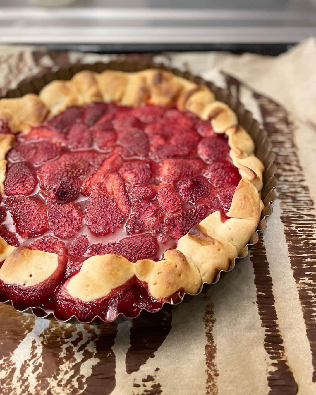 のインスタグラム：「これはまた、ずいぶんドキュメンタリーな苺のタルトだこと。  フランスを代表する甘い苺のガリゲットが特価だった。それでここぞとばかりに3パック買い込んで、2.5パックをきび砂糖、レモン汁、カルダモンパウダー、黒胡椒でマリネして、生地は市販のパットサブレ（タルト用のサブレ生地）を型に敷き詰めただけ。そこにマリネした苺を投入して、フチを織り込んでおしまい。  な、なんて簡単なんだ！これでもしも美味しかったら、私はもう一生お菓子の生地は作らないんではないか⁉️と危機感を覚えるほどの扱いやすさ👀  しかし、生の生地に生苺を合わせて焼くわけだから、当然苺はコンフィチュール状になる。それを一晩冷蔵庫で寝かせると、苺のペクチンが固まっていい感じなるわけなんですけど。  焼き上がったタルトを見て、私が食材と生地の合わせ方を知らないか、そもそもこの生地はまずタルトを空焼きしてから使うものだと知らないと思ったらしく、彼があれこれ心配げに指南し始めた。  うん、基本はわかってる。生地はプラムの巣タルトくらい軽い方が向いてる。たまたま買い置きがあったから、少々乱暴だけど焼いちゃいました❣️な感じだよ、と説明した。  たしかにカリッとしたタルトもいいんだけどさ、この果物のジュースがたっぷり沁みた底のふにゃふにゃの生地のところもなんか美味しいんだよね。  そういう、どことなくしみったれてるけど、家庭じゃないと味わえない気軽に作れるお菓子が、私は好きなんだよな。  #ねこしき　#猫沢飯　#猫沢銘品àparis  #猫パリ　#猫沢エミのインターナショナル五十路ライフシフト  #猫沢エミリーパリへ行く」