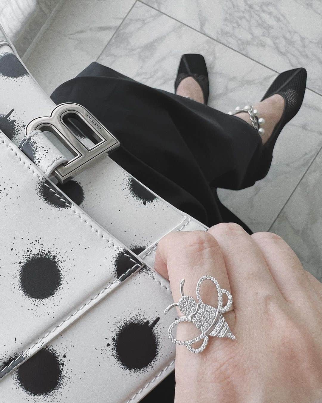のインスタグラム：「Details…🐝🐝🐝🖤🤍  @yon__jewelry と @thebees.jp コラボのミツバチリングのホワイトゴールド。  #balenciaga のペイント水玉バッグ。  #COEL #コエル のワンピースに、このメッシュのフラットが履きやすく、足首部分のパールとチェーンが着け外し簡単でかわいいんです🤍🤍🤍  #yon #ヨン #abuzzfromthebees #thebees #bee #ミツバチ #リング #miumiu #akiweng #翁安芸」